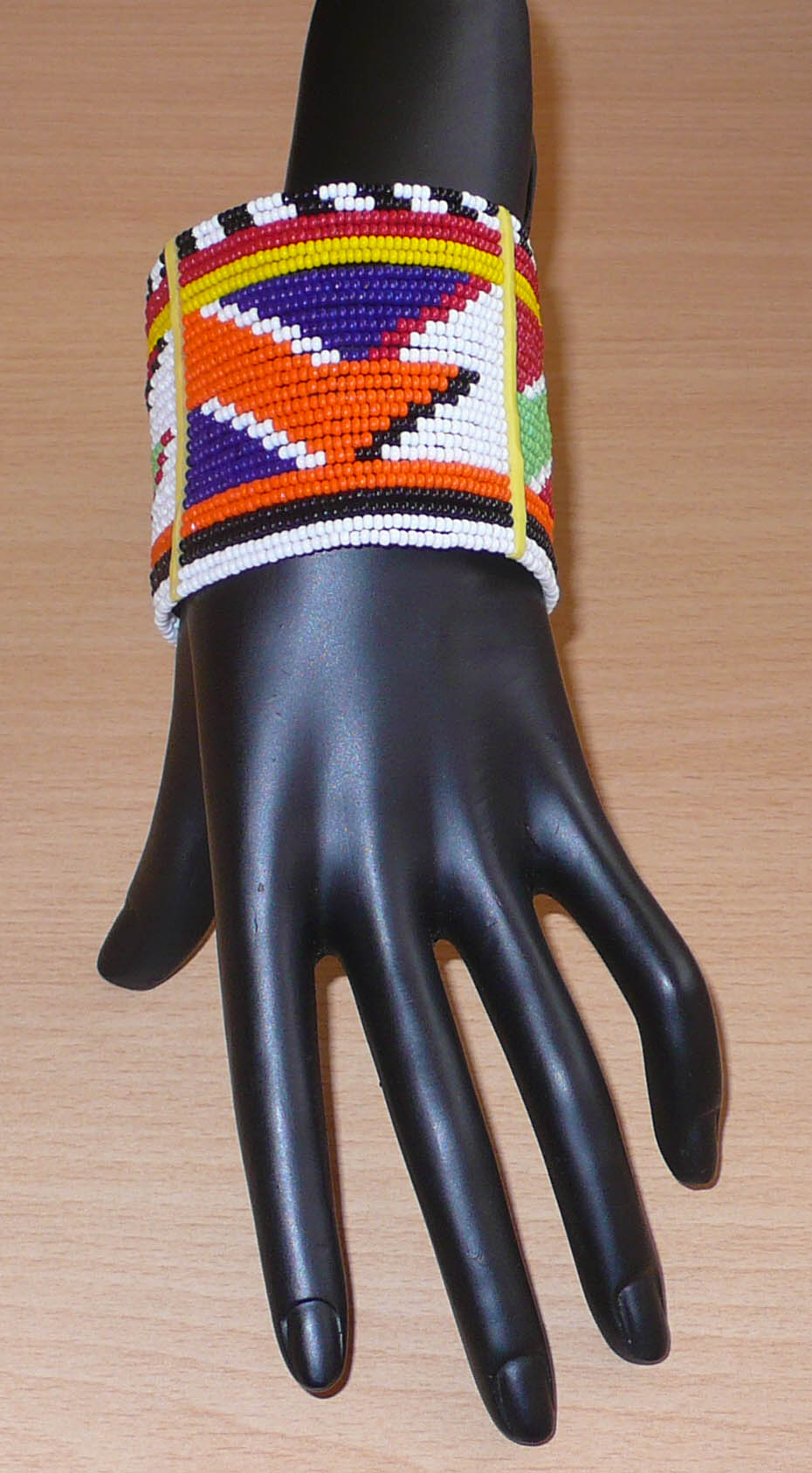 Bracelet africain traditionnel multi-rangs à motifs géométriques Massai composé de perles de rocaille multicolores enfilées sur vingt-six rangées de fils de fer fixés sur des charnières en plastique. Il s'attache avec des boutons pressions.