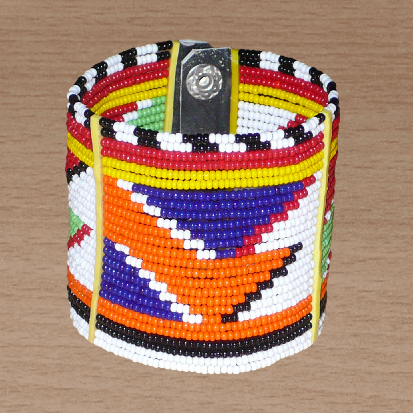 Bracelet africain traditionnel multi-rangs à motifs géométriques Massai composé de perles de rocaille multicolores enfilées sur vingt-six rangées de fils de fer fixés sur des charnières en plastique. Il s'attache avec des boutons pressions.