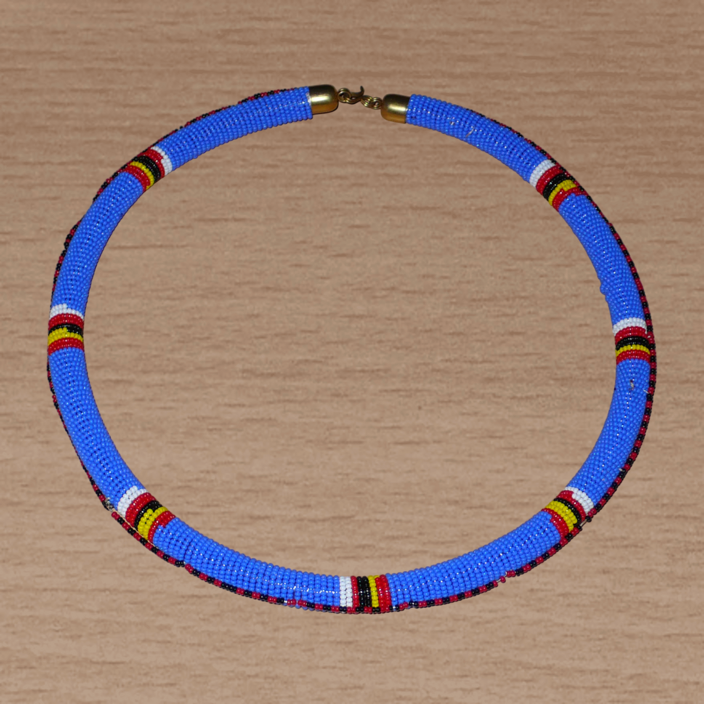 Collier africain Massai tubulaire composé de perles de rocaille principalement bleues, décoré de motifs ethniques perlés.