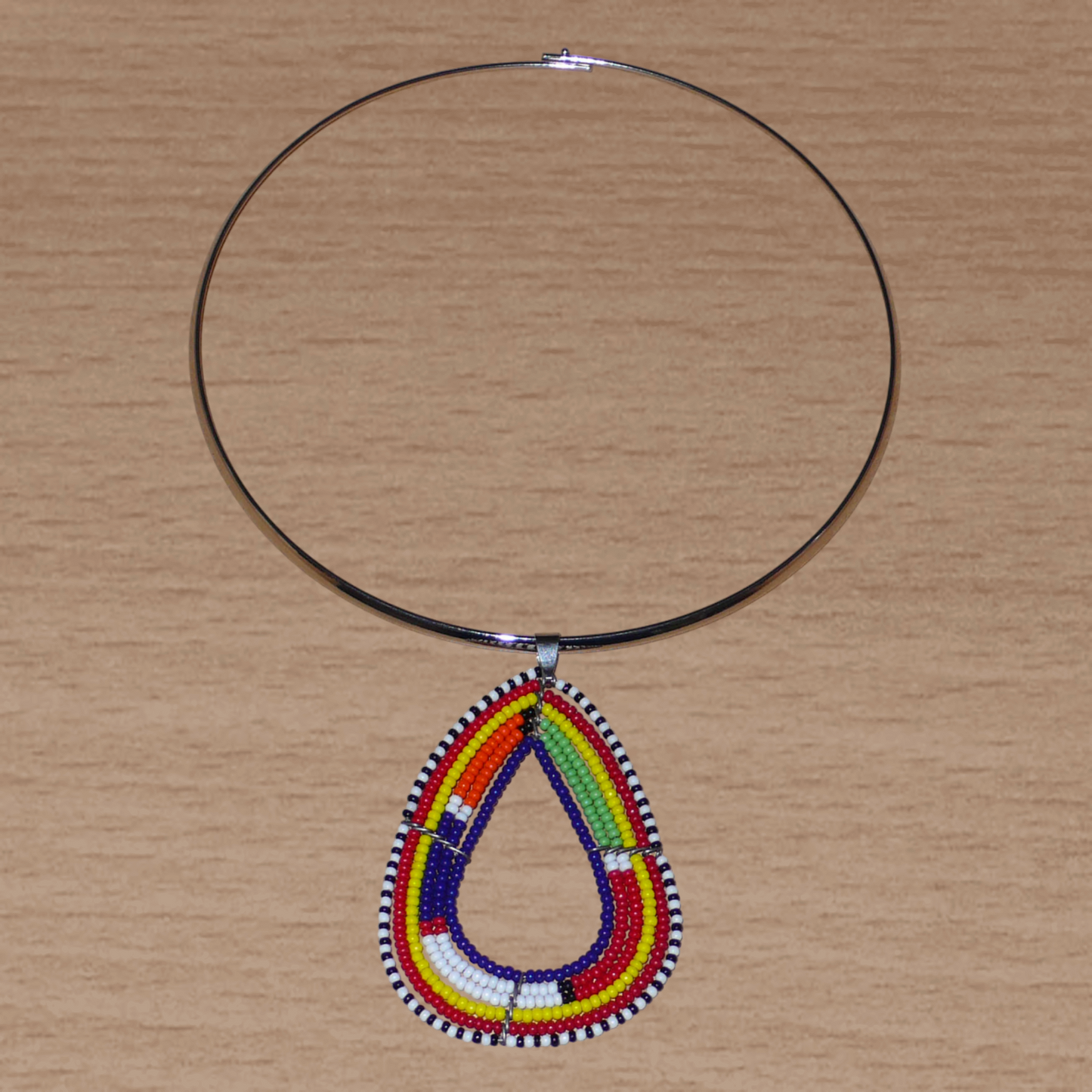 Collier africain composé d'un ras de cou en laiton agrémenté d'un pendentif Massai fait de perles de rocaille bleu foncé et multicolores.