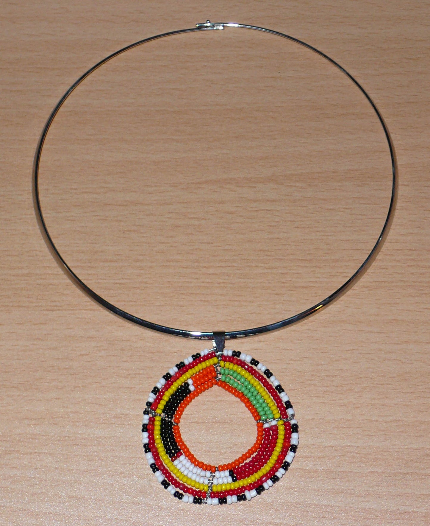 Collier ras de cou africain en laiton orné d'un médaillon Massai fait de perles de rocaille multicolores.