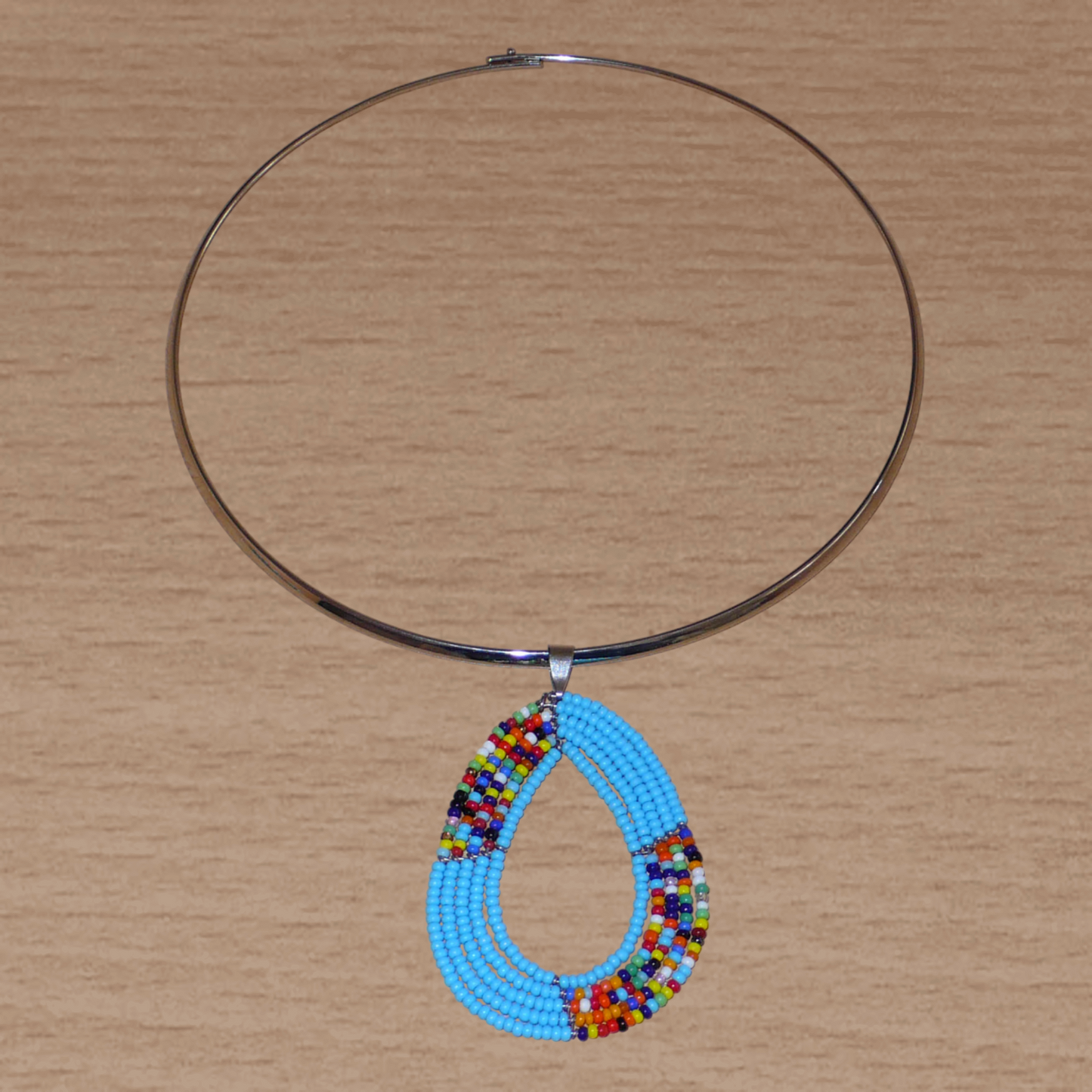 Collier ethnique bleu composé d'un ras de cou en laiton agrémenté d'un pendentif fait de perles de rocaille bleu ciel et multicolores enfilées sur cinq rangées de fils de fer montés en forme de goutte.