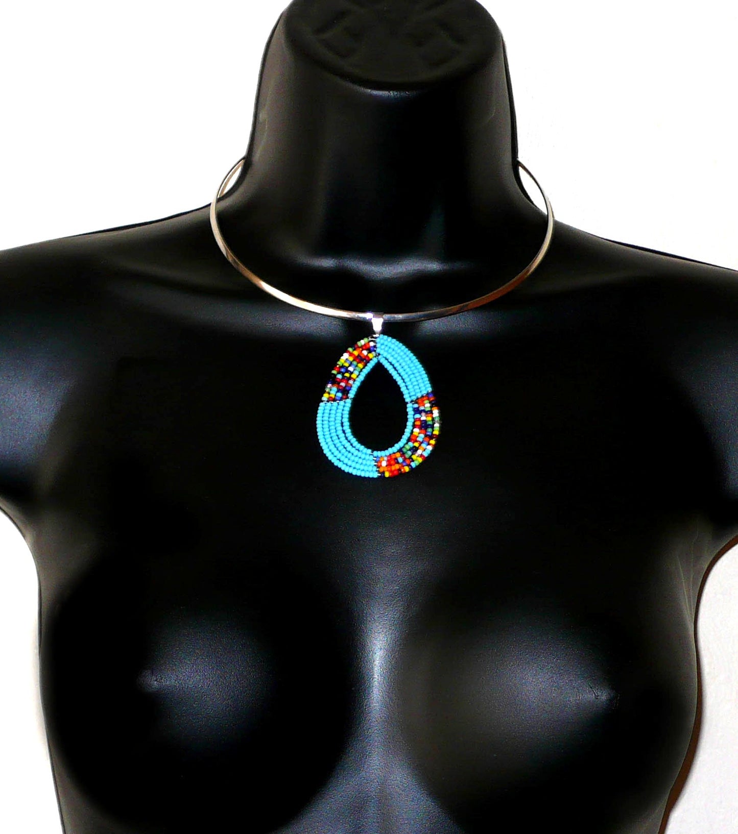 Collier ethnique bleu composé d'un ras de cou en laiton agrémenté d'un pendentif fait de perles de rocaille bleu ciel et multicolores enfilées sur cinq rangées de fils de fer montés en forme de goutte.