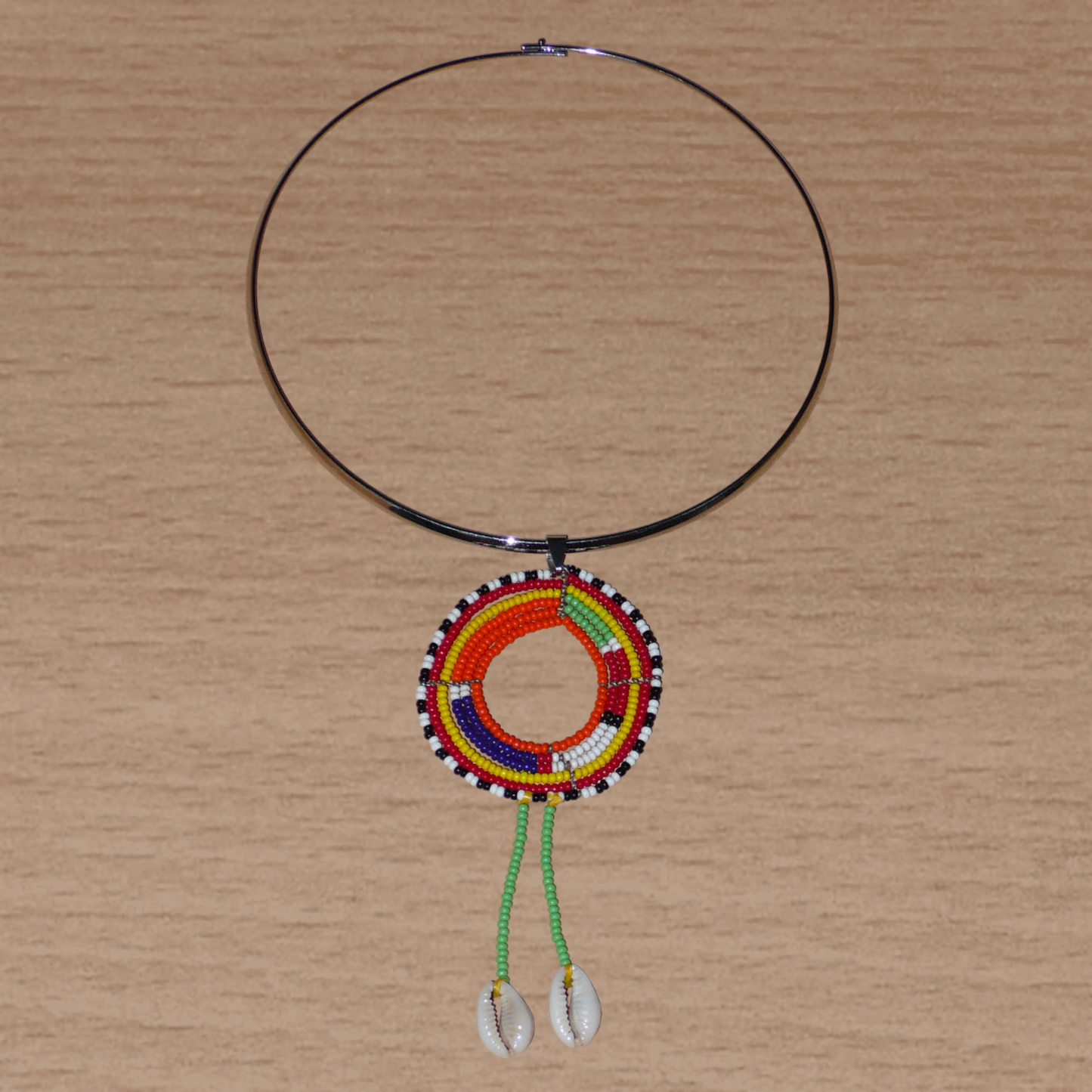 Collier africain se composant d'un ras de cou en laiton orné d'un long pendentif ethnique Massai en perles de rocaille vertes et multicolores et coquillages cauris.