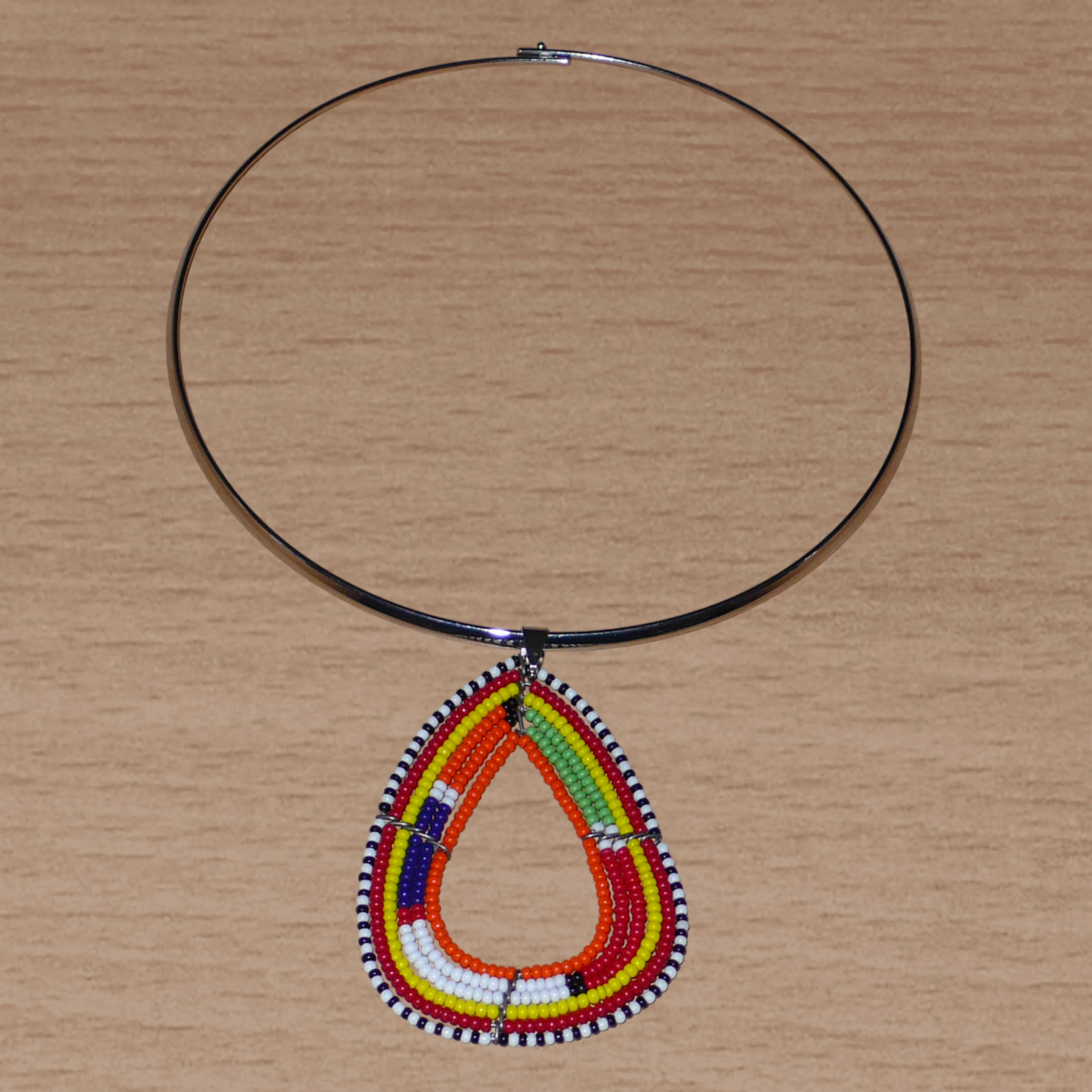 Collier africain composé d'un ras de cou en laiton orné d'un pendentif Massai fait de perles de rocaille orange et multicolores montées en forme de triangle aux bords arrondis.