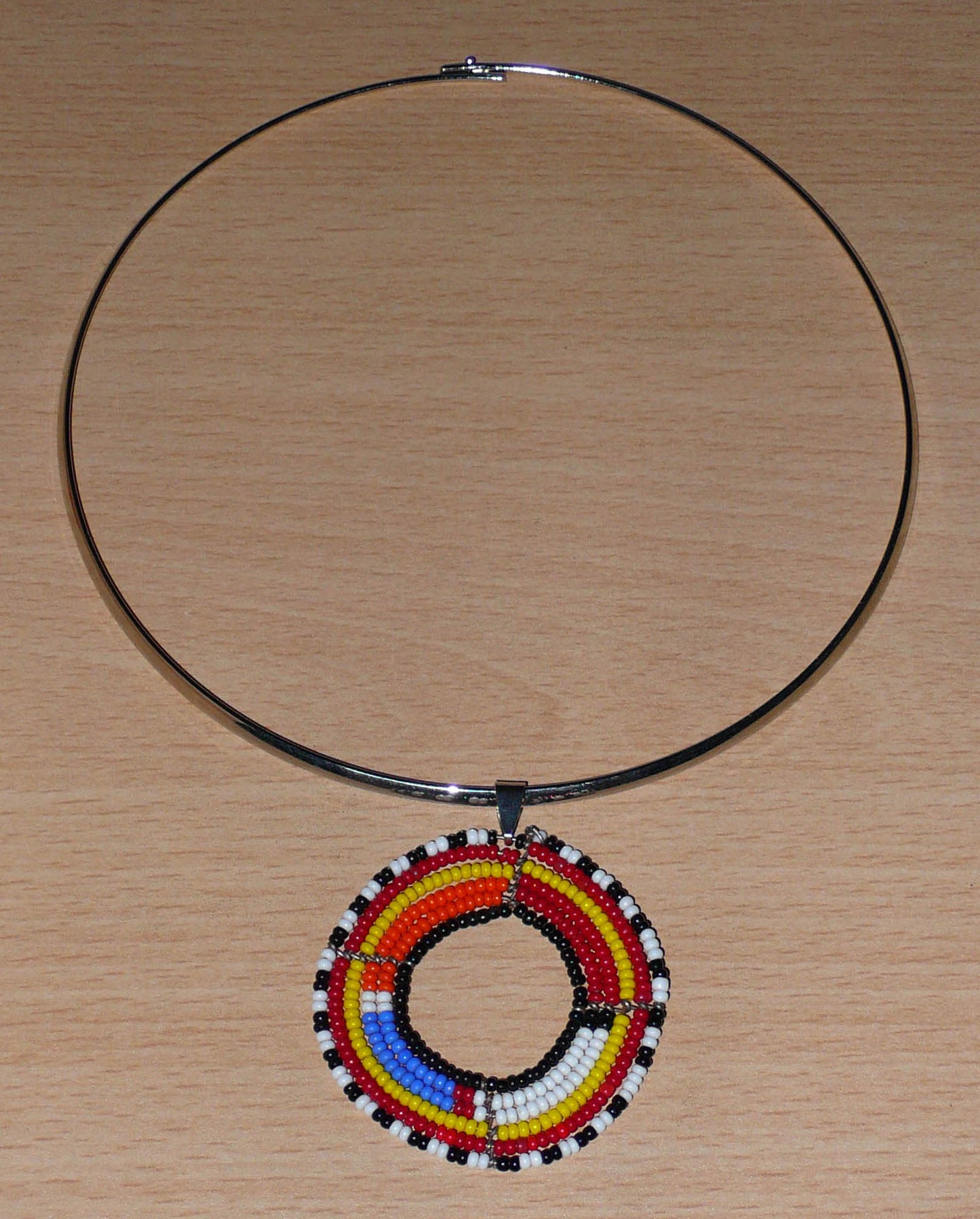 Collier ethnique fait d'un ras de cou en laiton orné d'un médaillon Massai composé de perles de rocaille multicolores.