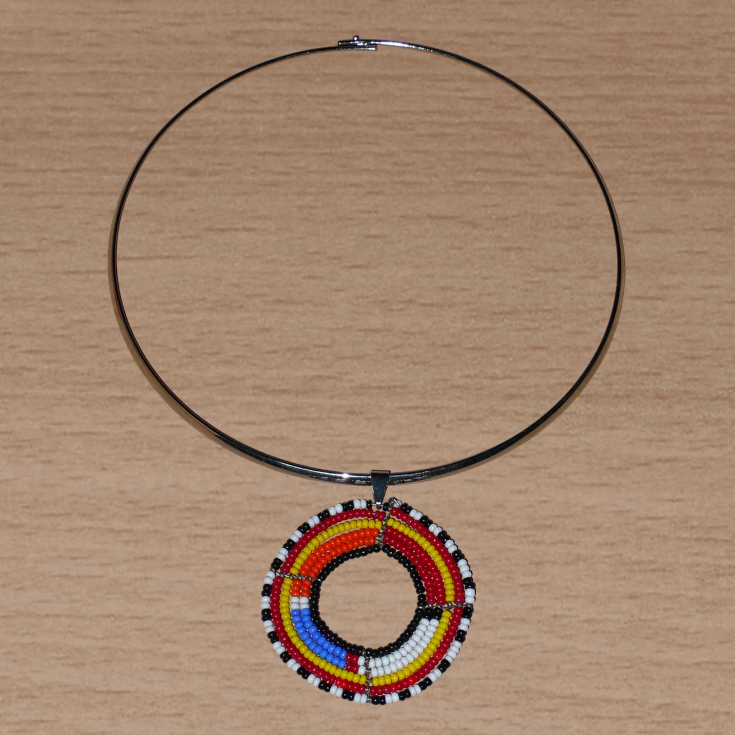 Collier ethnique fait d'un ras de cou en laiton orné d'un médaillon Massai composé de perles de rocaille multicolores.