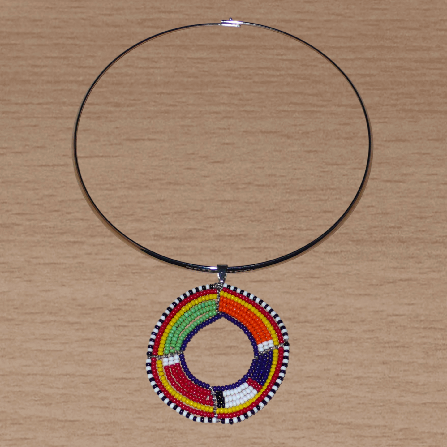 Bijou africain composé d'un collier ras de cou en laiton rehaussé d'un pendentif Massai rond fait de perles de rocaille multicolores.