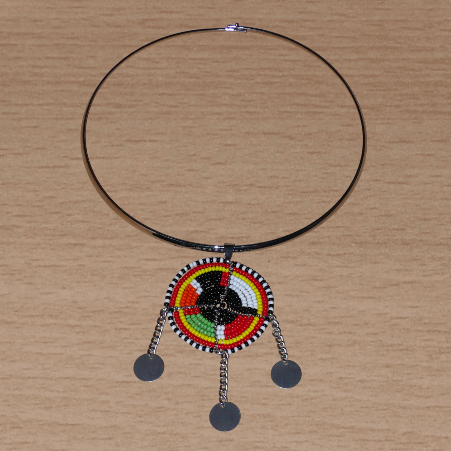Bijou africain composé d'un ras de cou en laiton agrémenté d'un pendentif fait de perles de rocaille noires et multicolores et décoré de petits disques métalliques.
