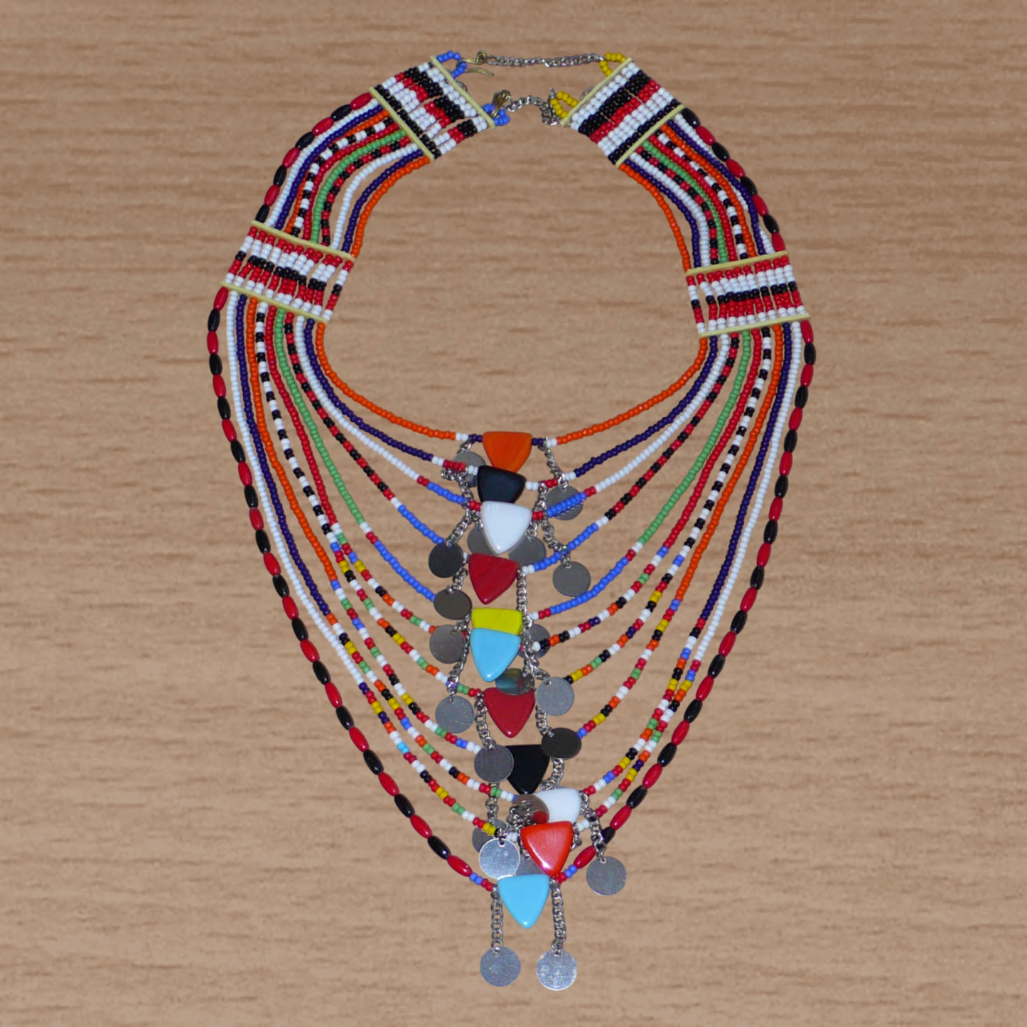 Collier africain traditionnel Massai composé de plusieurs rangées de perles multicolores ; des perles triangulaires et des pastilles en métal décorent le collier en son centre.