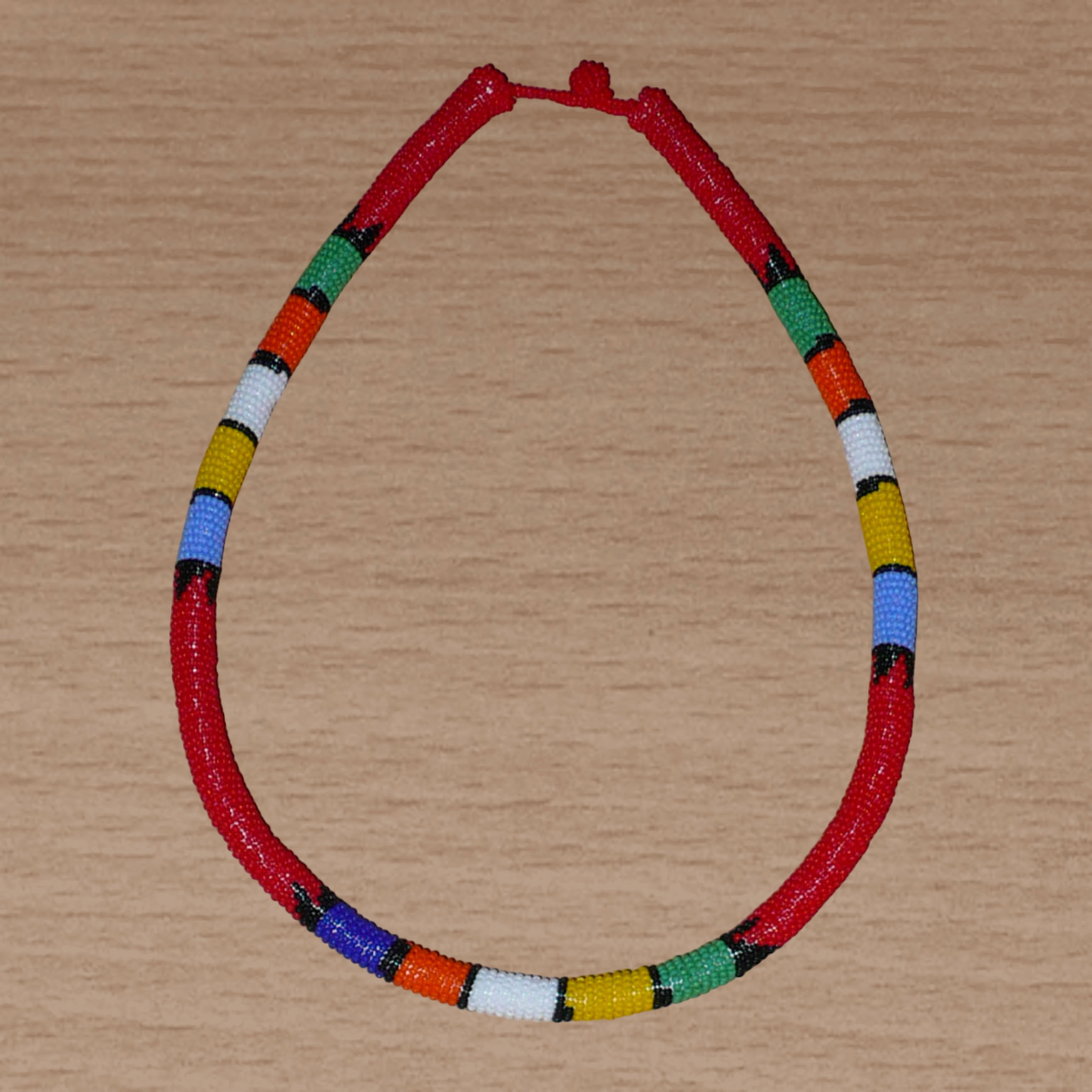 Collier africain traditionnel rouge à motifs zoulous multicolores fabriqué en Afrique du Sud ; il se compose de perles de rocaille enroulées autour d'un tube en plastique.