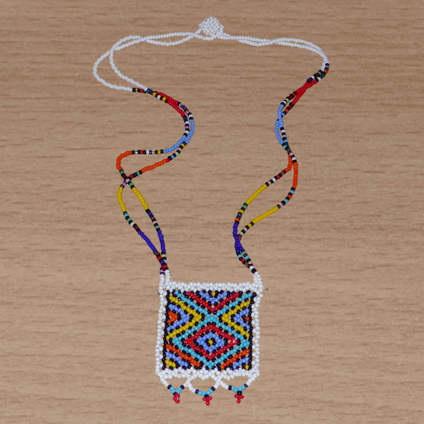 Collier africain zoulou en perles de rocaille blanches et multicolores agrémenté d'un pendentif carré à motifs ethniques traditionnels.