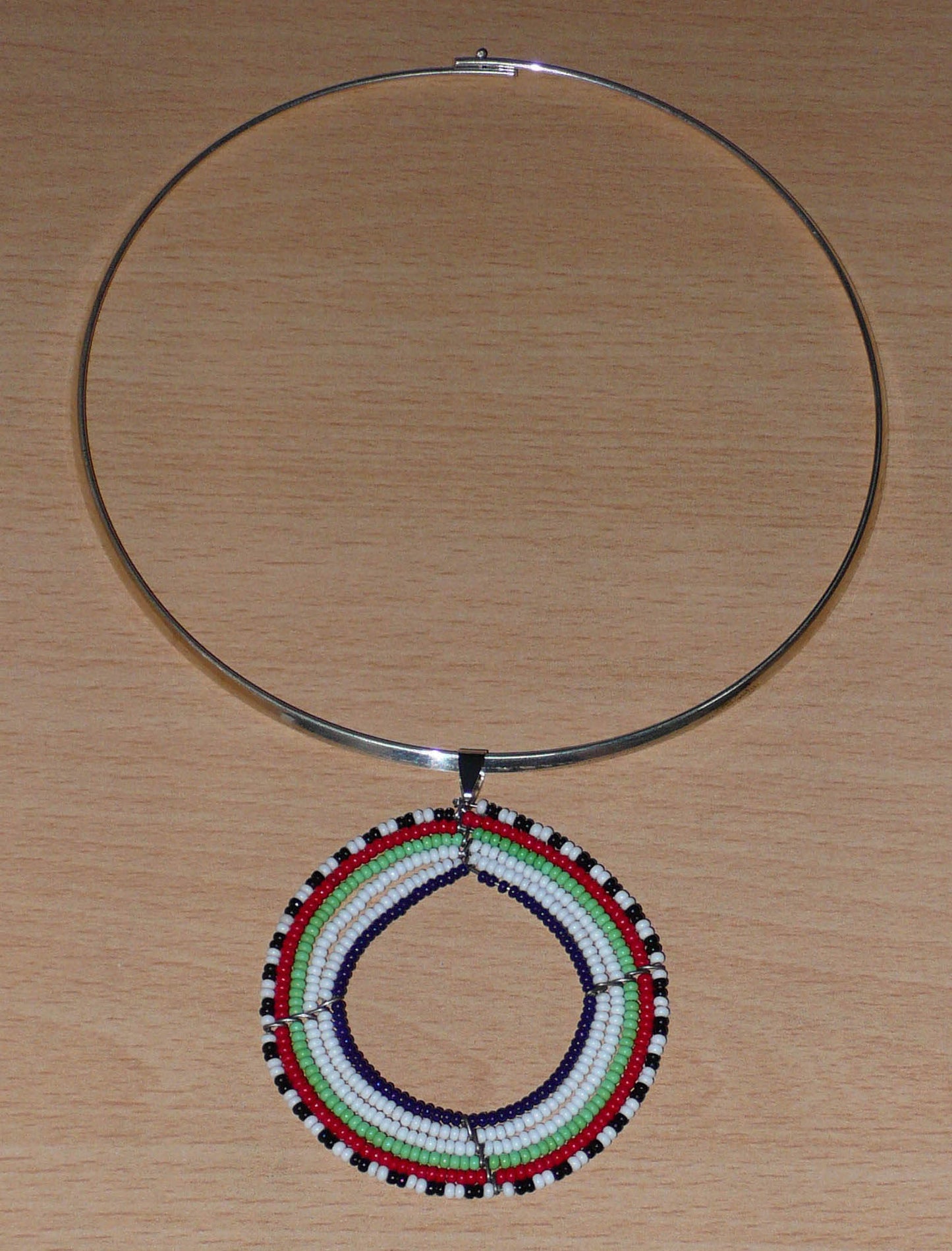 Collier africain Massai contemporain composé d'un ras de cou en laiton agrémenté d'un large médaillon fait de perles de rocaille blanches, vertes, rouges, noires et bleu marine.