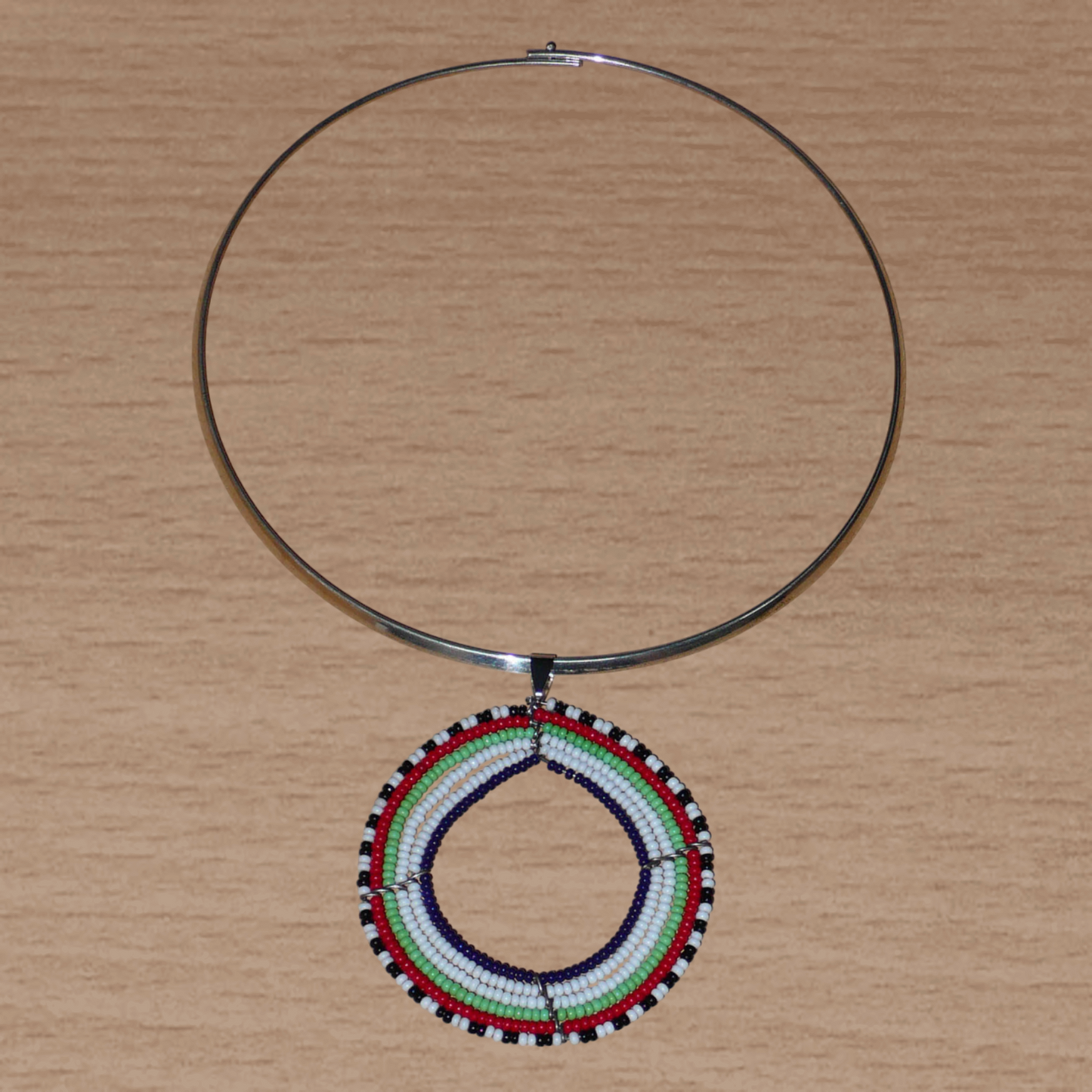 Collier africain Massai contemporain composé d'un ras de cou en laiton agrémenté d'un large médaillon fait de perles de rocaille blanches, vertes, rouges, noires et bleu marine.