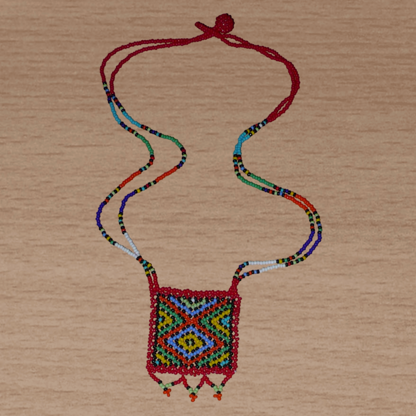 Collier africain "Zulu Love Letter" avec pendentif orné de motifs ethniques ; il se compose d'un tissage de perles de rocaille rouges et multicolores.