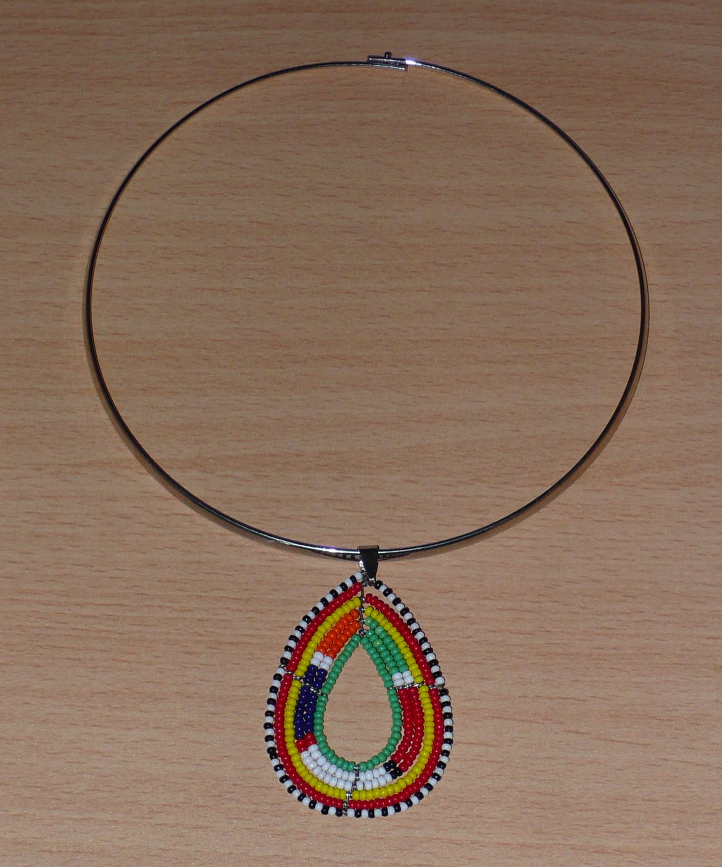 Collier africain Massai composé d'un ras de cou en laiton agrémenté d'un pendentif fait de perles de rocaille vertes et multicolores enfilées sur six rangées de fils de fer montés en forme de goutte.