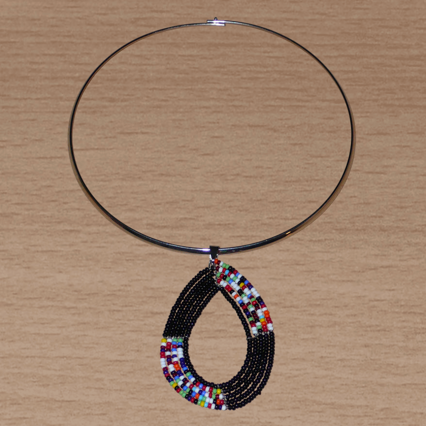 Collier ras de cou en laiton orné d'un long pendentif en forme de goutte composé de perles de rocaille noires et multicolores.