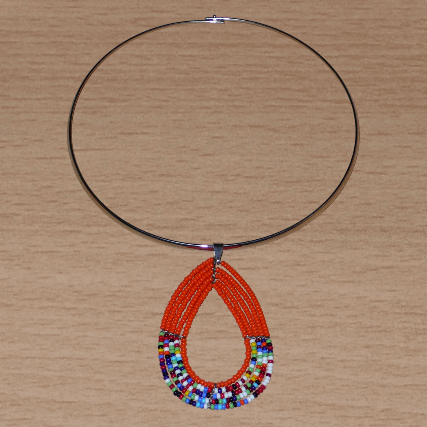 Collier ras de cou en laiton orné d'un long pendentif en forme de goutte composé de perles de rocaille orange et multicolores.