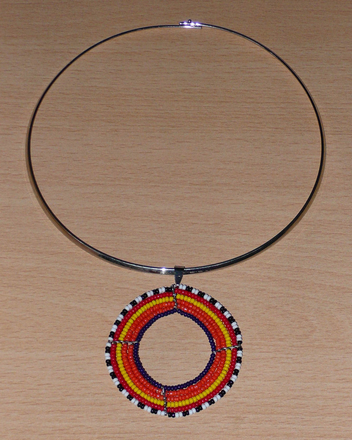 Collier ethnique orange composé d'un ras de cou en laiton orné d'un large médaillon fait de perles de rocaille.