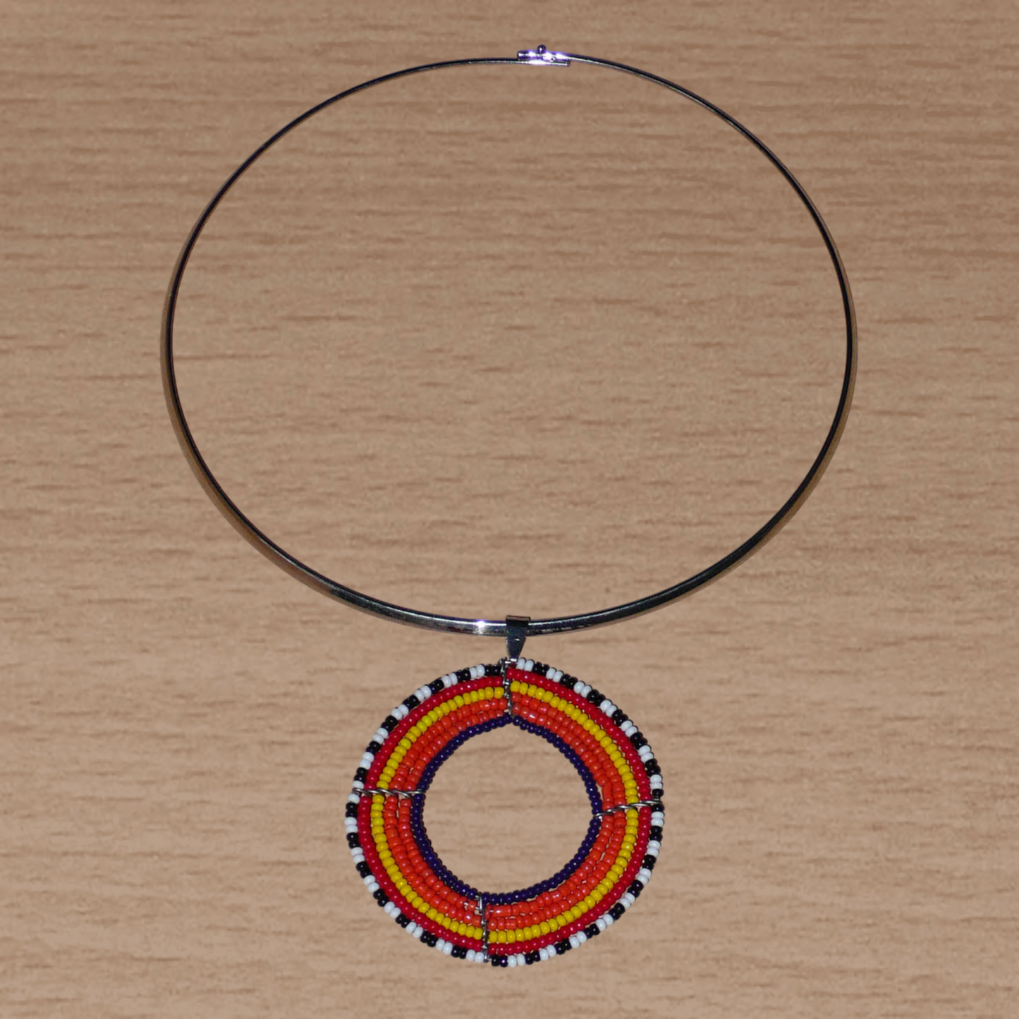 Collier ethnique orange composé d'un ras de cou en laiton orné d'un large médaillon fait de perles de rocaille.