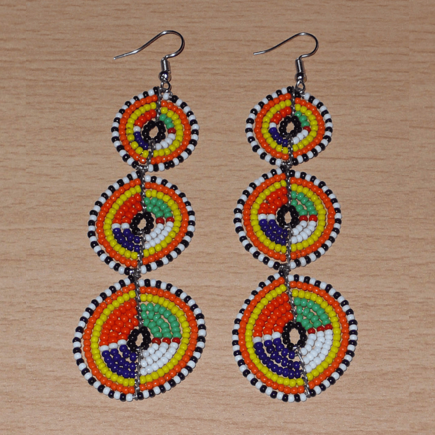 Longues boucles d'oreilles ethniques afro chic composées de perles de rocaille multicolores montées en trois cercles superposés. Elles mesurent 10,5 cm de long et 3 cm de large.