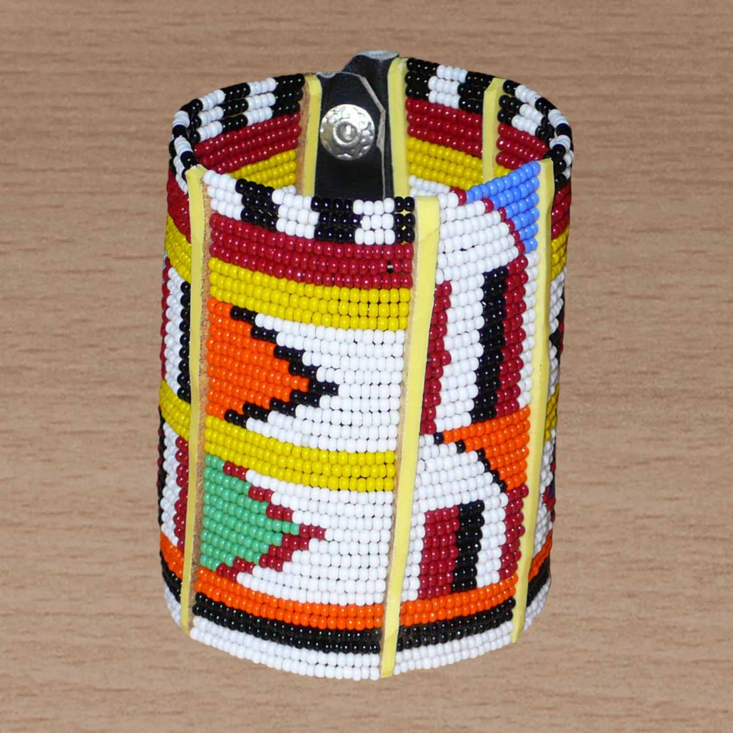 Manchette africaine multi-rangs à motifs ethniques traditionnels Massai composée de trente-six rangées de perles de rocaille multicolores glissées sur des fils de fer fixés sur des charnières en plastique jaune.