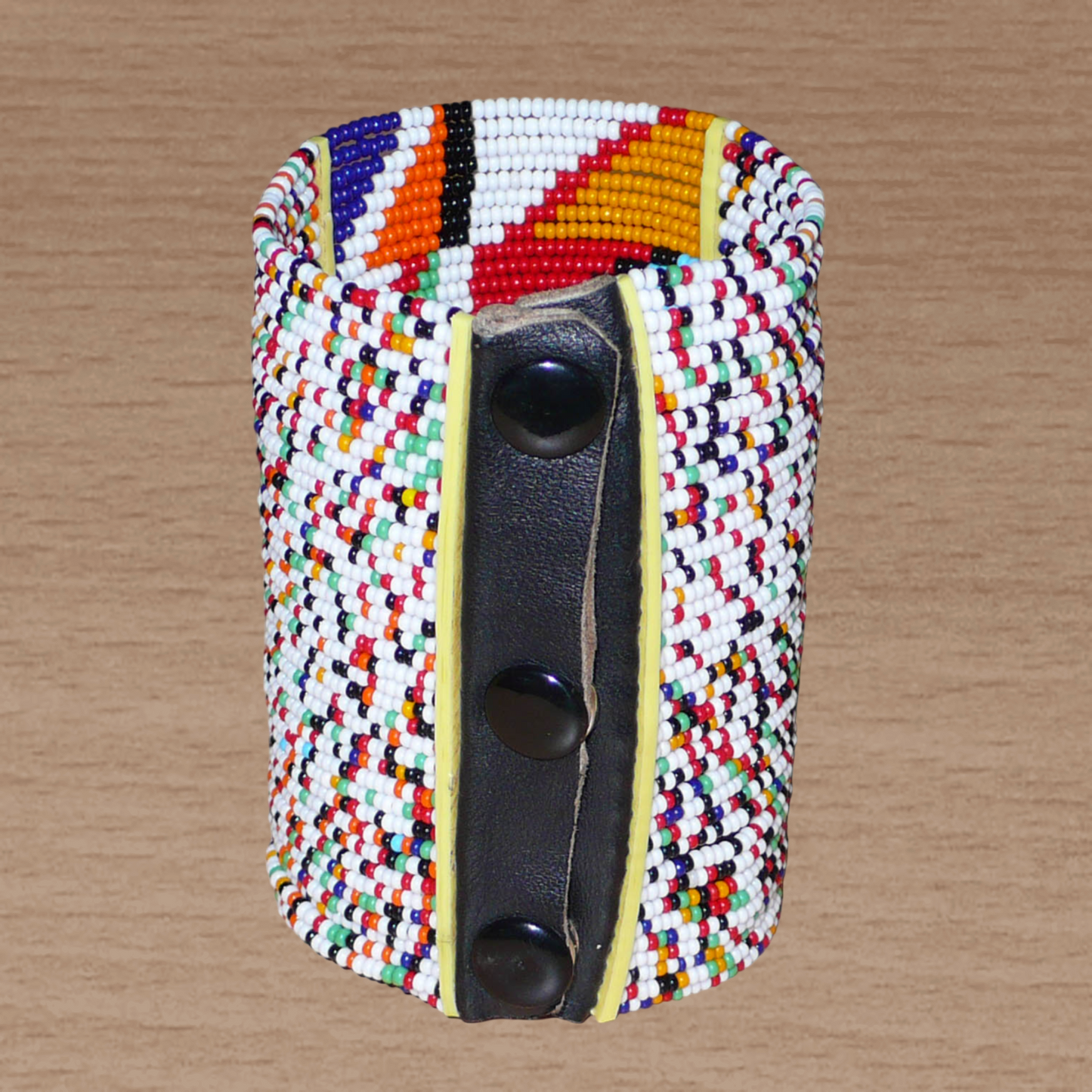 Manchette haute multi-rangs à motifs géométriques ethniques Massai composée de perles de rocaille multicolores ; elle s'attache avec trois boutons pressions.