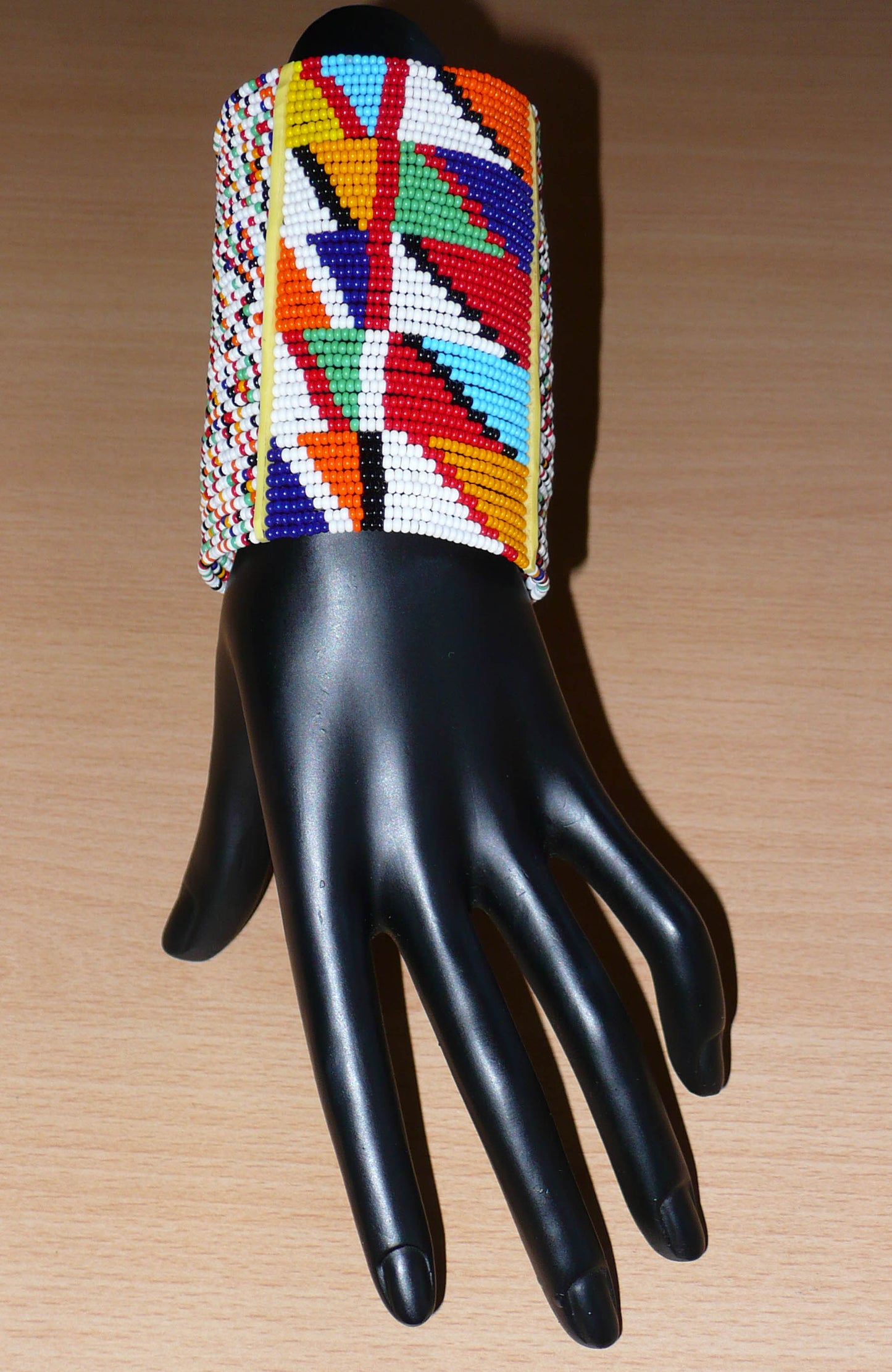Manchette haute multi-rangs à motifs géométriques ethniques Massai composée de perles de rocaille multicolores ; elle s'attache avec trois boutons pressions.