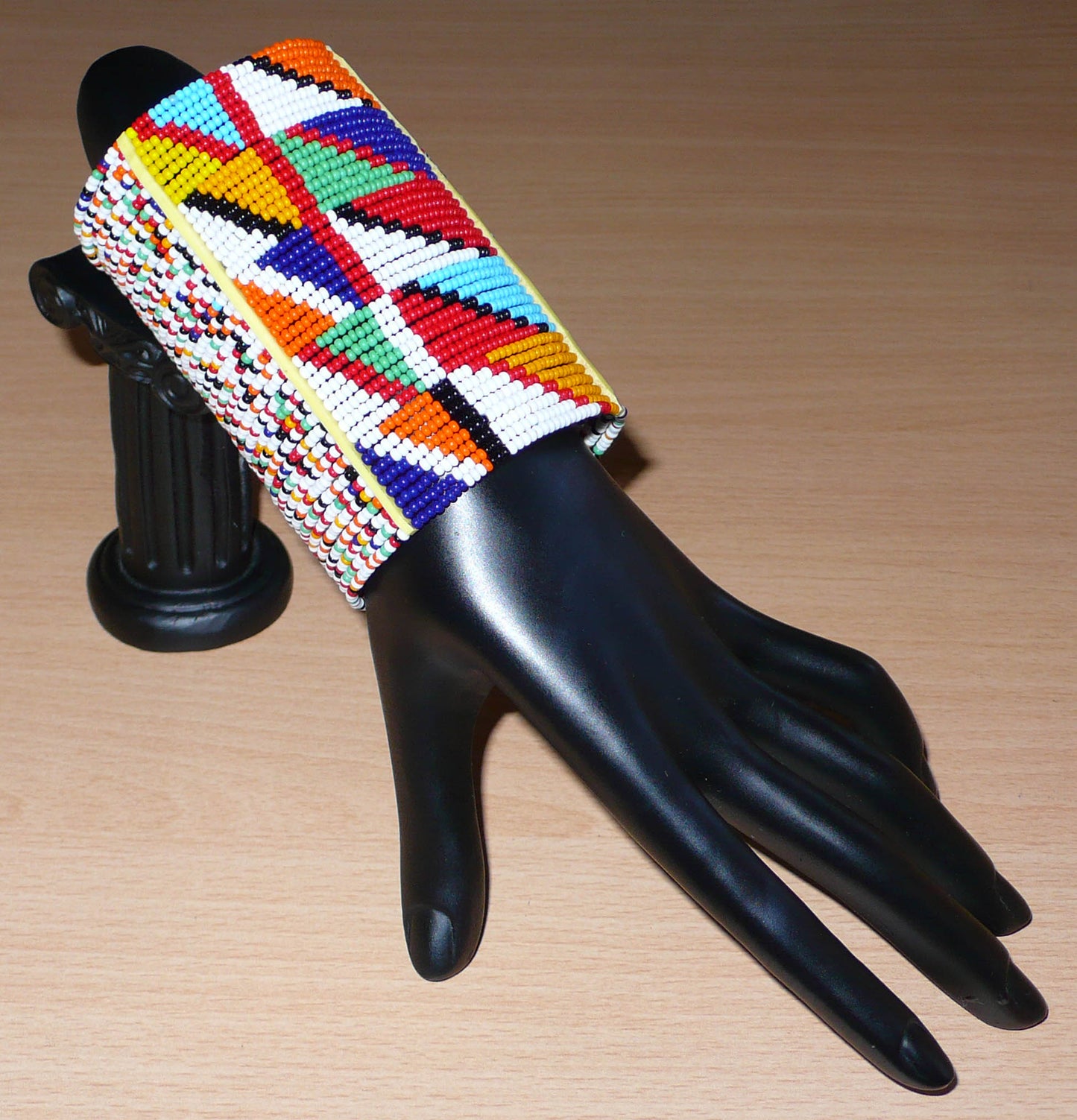 Manchette haute multi-rangs à motifs géométriques ethniques Massai composée de perles de rocaille multicolores ; elle s'attache avec trois boutons pressions.