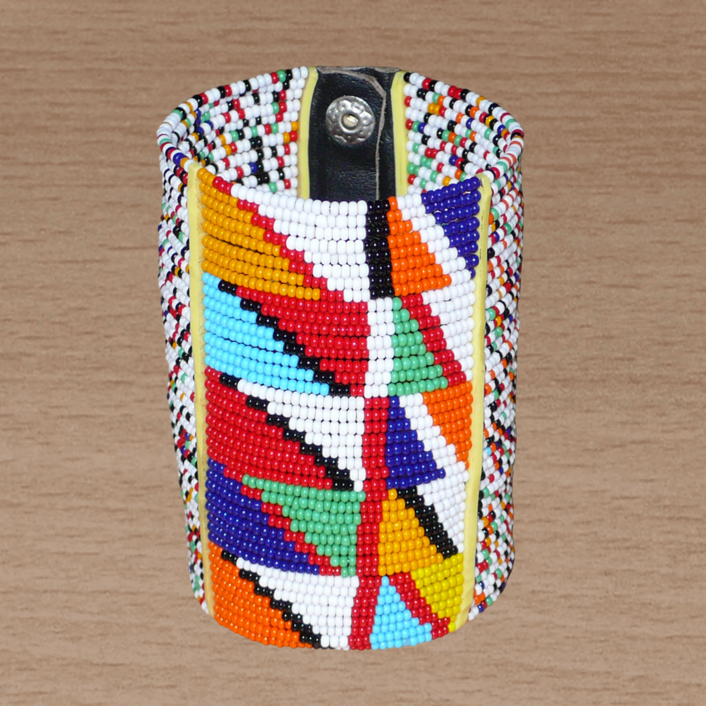 Manchette haute multi-rangs à motifs géométriques ethniques Massai composée de perles de rocaille multicolores ; elle s'attache avec trois boutons pressions.