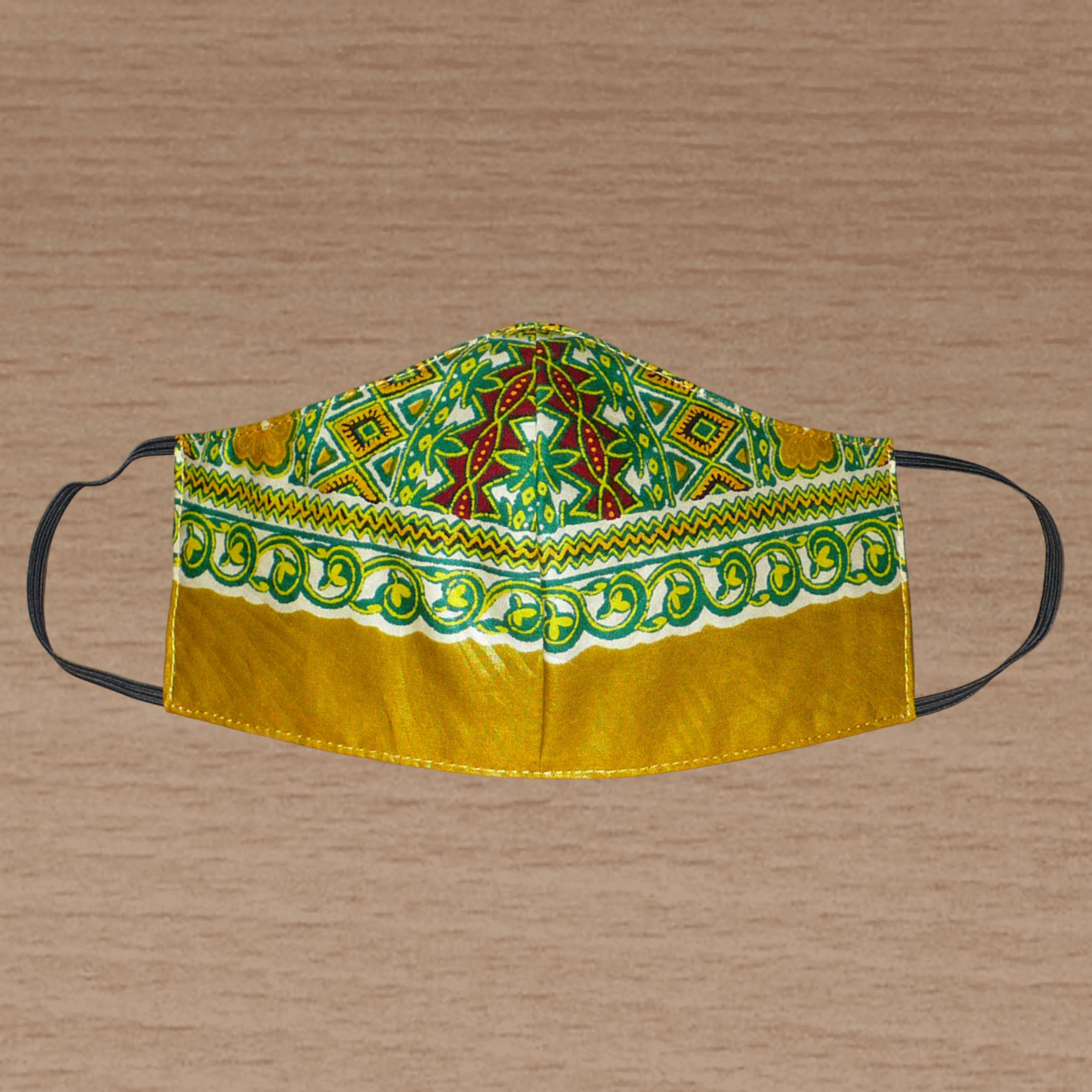 Masque facial textile ajusté en tissu africain imprimé de motifs ethniques multicolores ; il se porte avec des élastiques. En vue d'une utilisation eco-friendly, ce masque est lavable et réutilisable. Ce masque à l'allure exotique mesure 21 cm de long, et 40 cm en comptant les élastiques ; il a une hauteur de 12 cm (du haut du nez jusqu'au menton) et une largeur sur les côtés de 7 cm. Il peut être porté par une femme ou par un homme. Pour des raisons évidentes d'hygiène, les retours et les échanges de ma