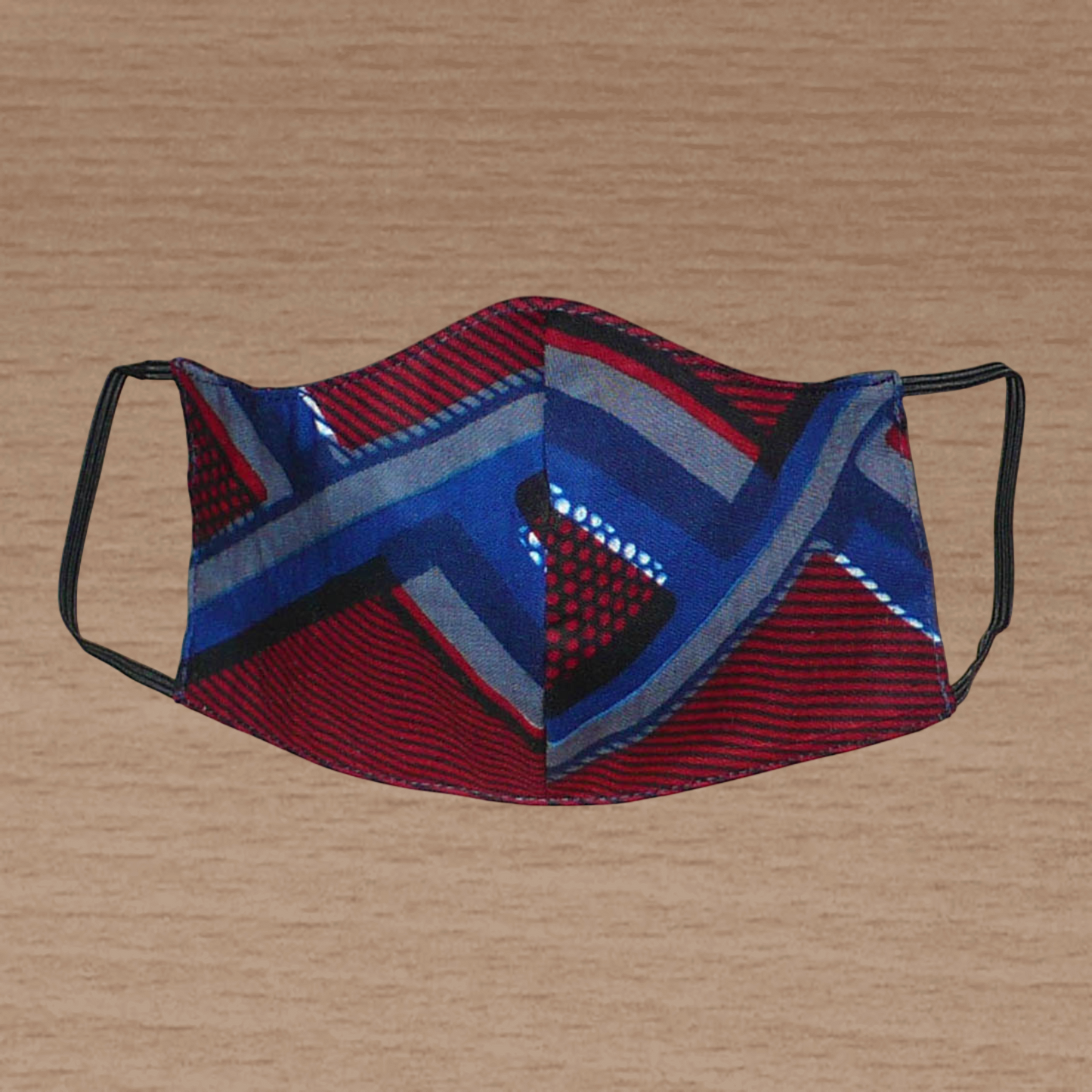 Masque facial pour homme en tissu africain en coton imprimé de motifs bordeaux, bleus, gris et noirs ; il se porte avec des élastiques. En vue d'une utilisation éco-responsable, ce masque est lavable et réutilisable.