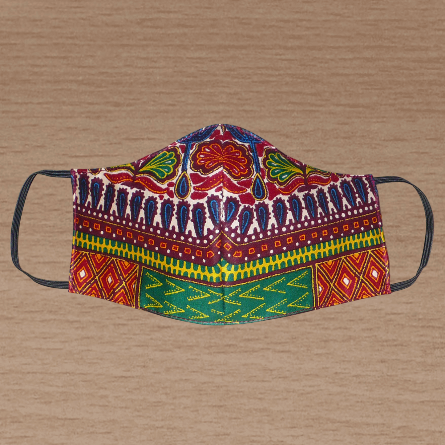 Masque facial ajusté, coupé et cousu dans un tissu en coton à motifs africains ; lavable et réutilisable, il se porte avec des élastiques.