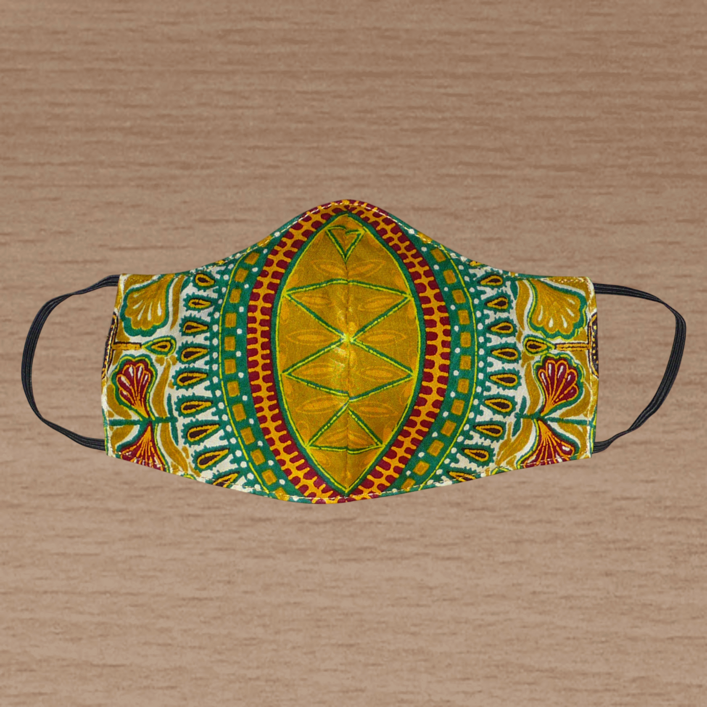 Masque facial en tissu africain jaune d'or imprimé de motifs exotiques multicolores ; il se porte avec des élastiques. En vue d'un usage éco-responsable, il est lavable et réutilisable.
