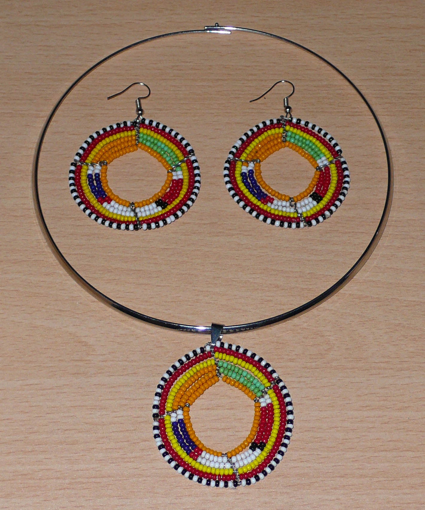 Parure de bijoux africains Massai composée d'un collier ras de cou en laiton orné d'un médaillon fait de perles de rocaille orange et multicolores, et d'une paire de boucles d'oreilles rondes assorties.