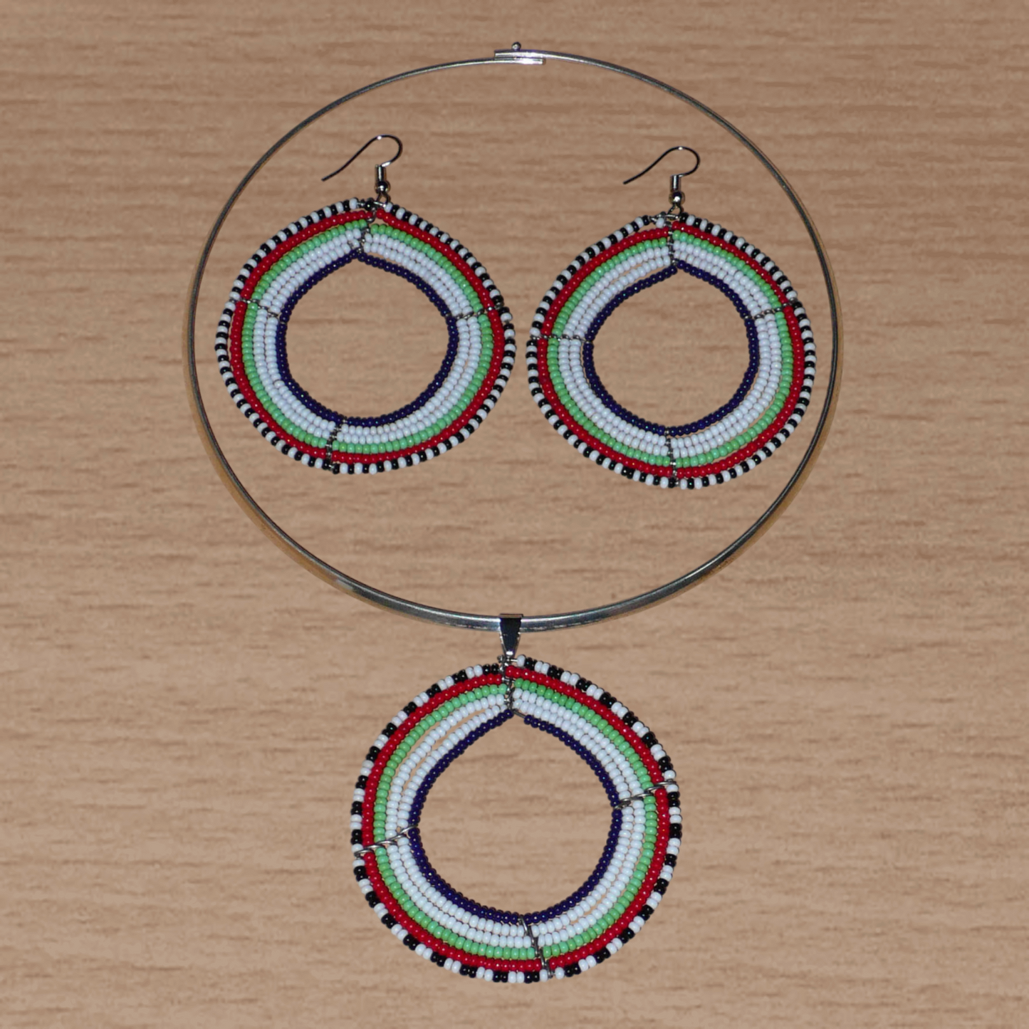 Parure de bijoux africains Massai au style hippie chic des années 70 composée d'un collier ras de cou en laiton orné d'un large médaillon fait de perles de rocaille blanches, vertes, rouges, noires et bleu marine, et d'une paire de boucles d'oreilles rondes assorties.