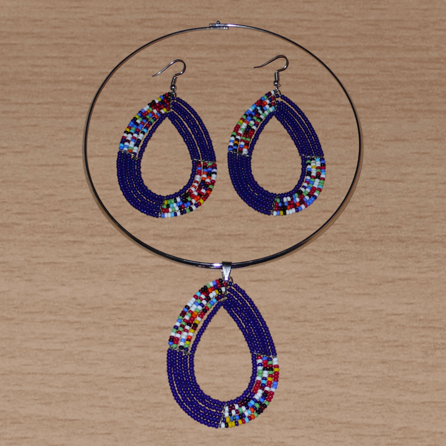 Parure de bijoux ethniques Massai comprenant un collier ras de cou orné d'un pendentif en forme de goutte fait de perles de rocaille bleu foncé et multicolores, ainsi qu'une paire de boucles d'oreilles assorties.