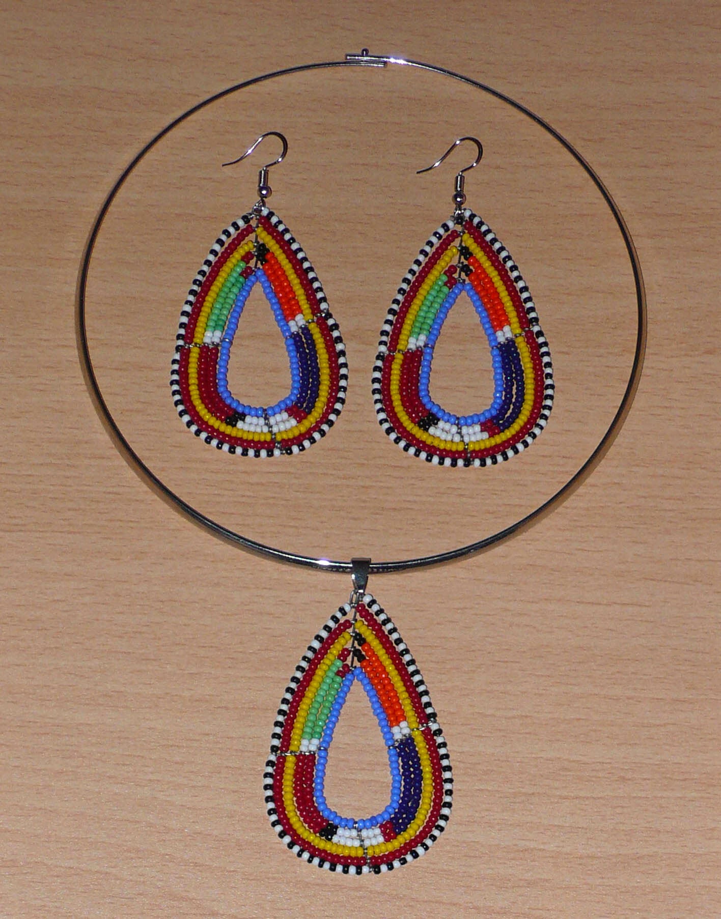 Parure de bijoux africains à motifs ethniques Massai composée d'un collier ras de cou agrémenté d'un pendentif en forme de goutte fait de perles de rocaille bleues et multicolores, et d'une paire de boucles d'oreilles assorties au collier.