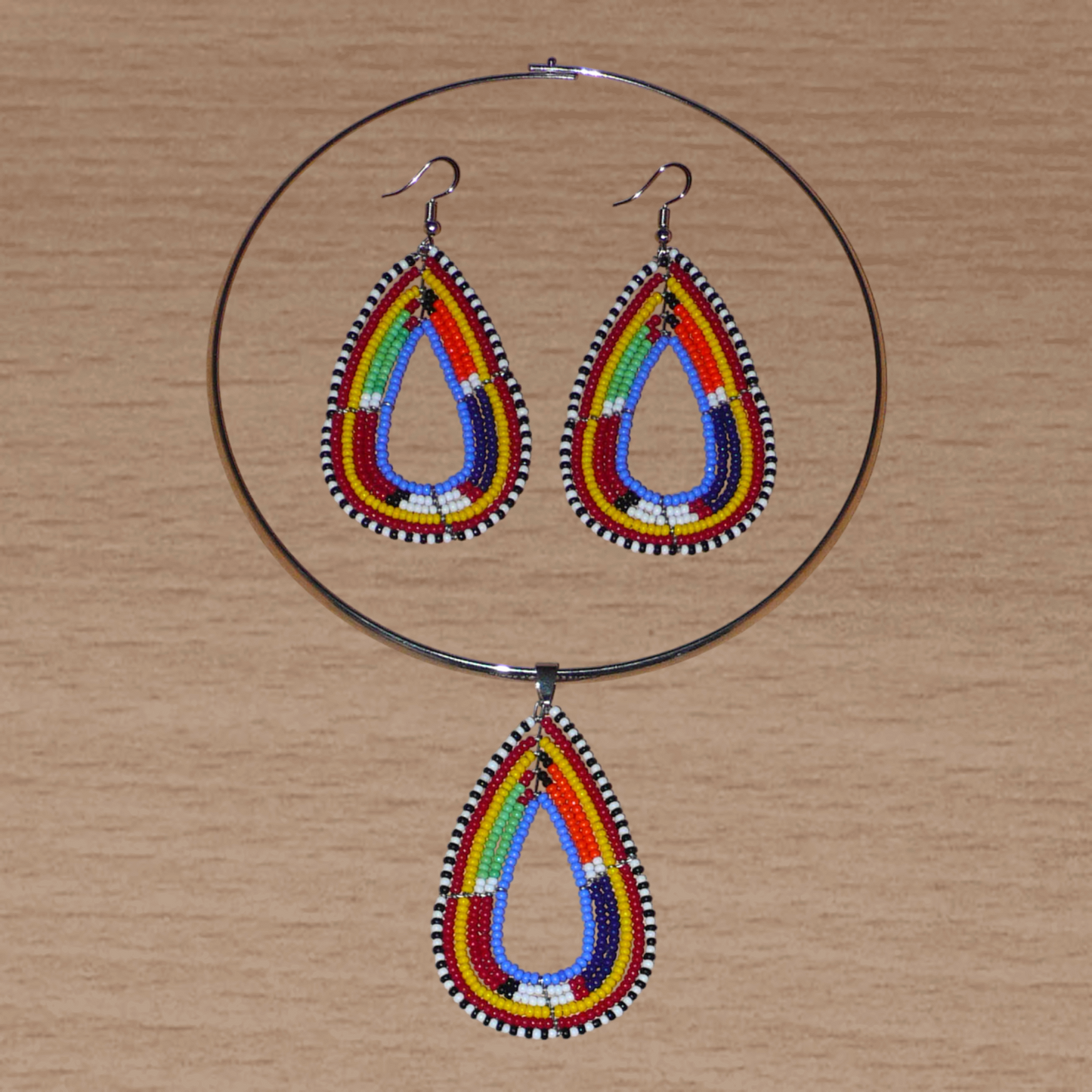 Parure de bijoux africains à motifs ethniques Massai composée d'un collier ras de cou agrémenté d'un pendentif en forme de goutte fait de perles de rocaille bleues et multicolores, et d'une paire de boucles d'oreilles assorties au collier.