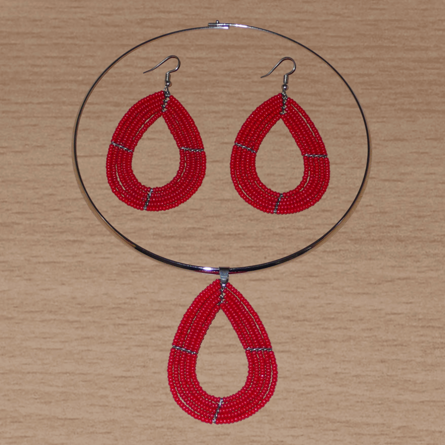 Parure de bijoux rouges composée d'un collier ras de cou en laiton agrémenté d'un pendentif multi-rangs en forme de goutte, et d'une paire de boucles d'oreilles assorties.