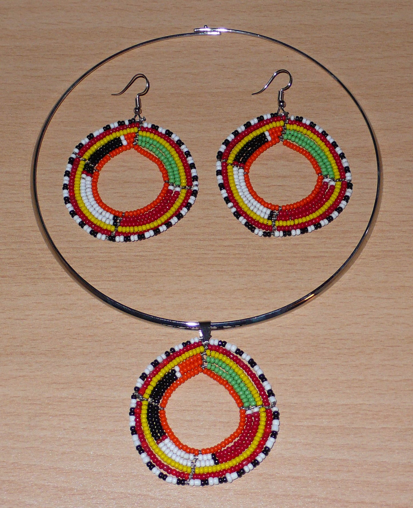 Parure de bijoux africains Massai composée d'un collier ras de cou en laiton orné d'un médaillon fait de perles de rocaille multicolores, et d'une paire de boucles d'oreilles assorties.