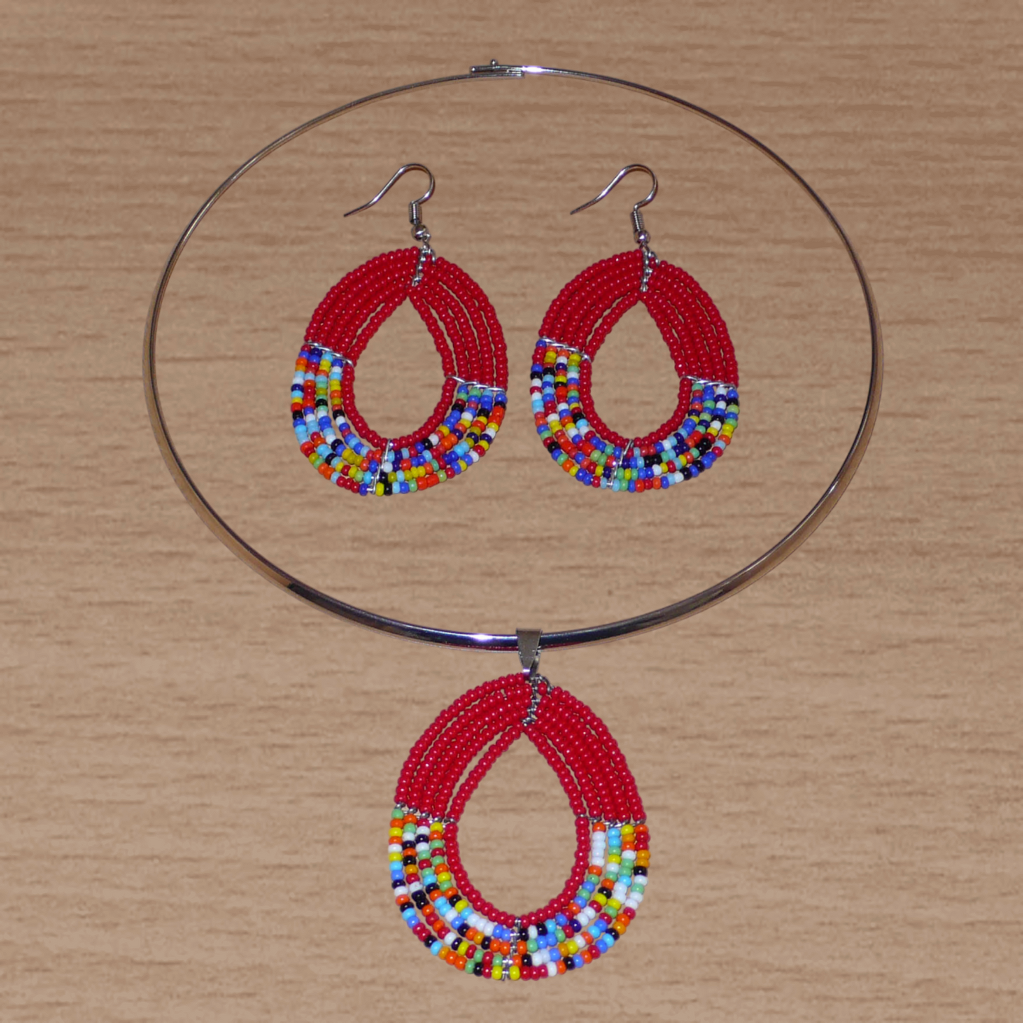 Parure de bijoux africains rouges et multicolores composée d'un collier ras de cou en laiton orné d'un pendentif en forme de goutte fait de perles de rocaille, et d'une paire de boucles d'oreilles assorties.