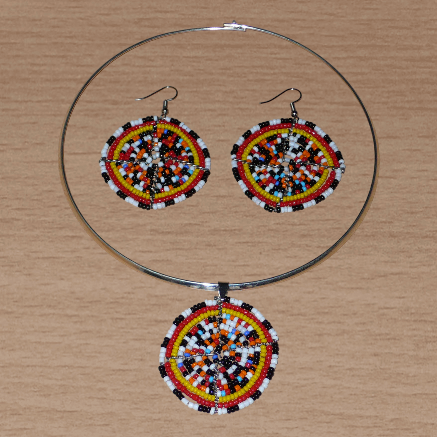 Parure de bijoux ethniques se composant d'un collier ras de cou en laiton orné d'un médaillon fait d'un mélange de perles de rocaille, et d'une paire de boucles d'oreilles rondes assorties.