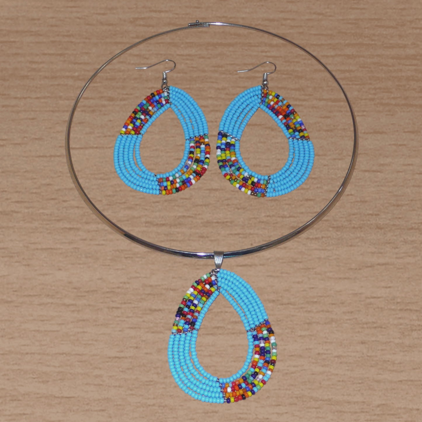 Parure de bijoux ethniques bleus aux accents bohème chic composée d'un collier ras de cou orné d'un pendentif fait de perles de rocaille bleu ciel et multicolores montées en forme de goutte, et d'une paire de boucles d'oreilles assorties.