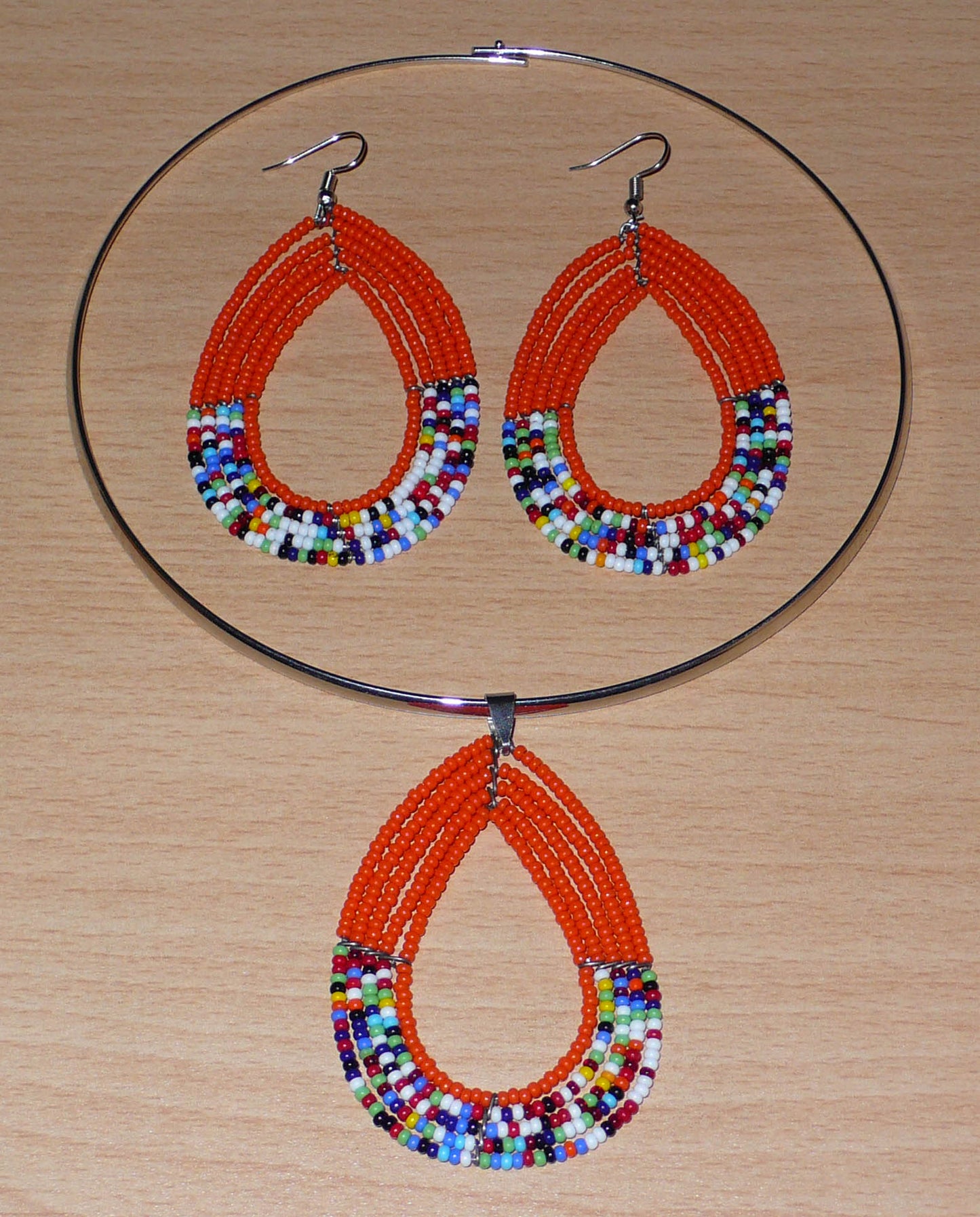 Parure de bijoux orange et multicolore composée d'un collier ras de cou en laiton orné d'un long pendentif en perles de rocaille montées en forme de goutte, et d'une paire de boucles d'oreilles assorties au collier.