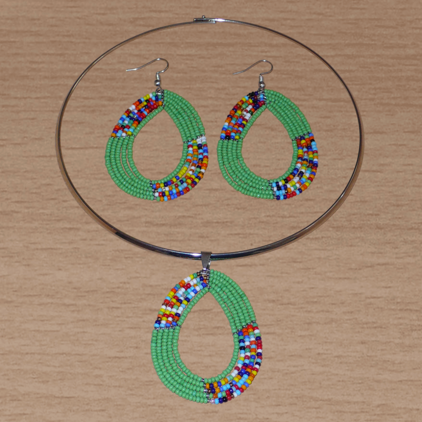 Parure contemporaine de bijoux ethniques verts aux accents bohème composée d'un collier ras de cou en laiton agrémenté d'un pendentif en perles de rocaille vertes et multicolores glissées sur cinq rangées de fils de fer montés en forme de goutte, et d'une paire de boucles d'oreilles assorties.