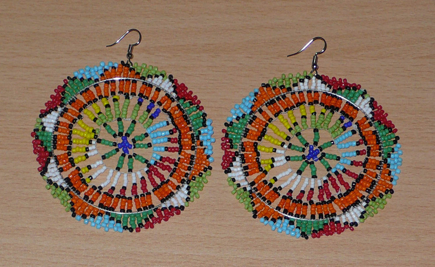 Boucles d'oreilles sud-africaines rondes surdimensionnées à motifs zoulous composées de perles de rocaille multicolores. Longues et larges, elles mesurent 10 cm de long et 8,5 cm de large, et se portent sur des oreilles percées.
