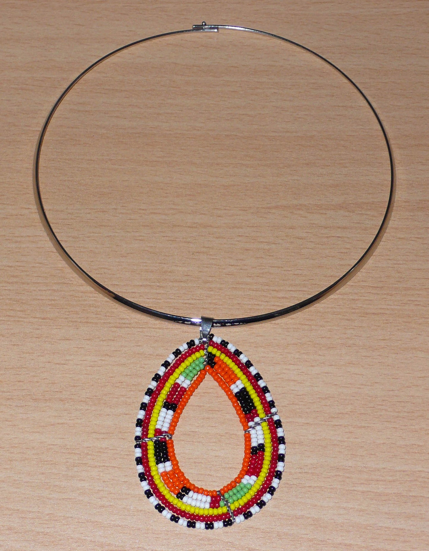 Collier africain Massai composé d'un ras de cou en laiton orné d'un long pendentif fait de perles de rocaille orange et multicolores montées en forme de goutte.