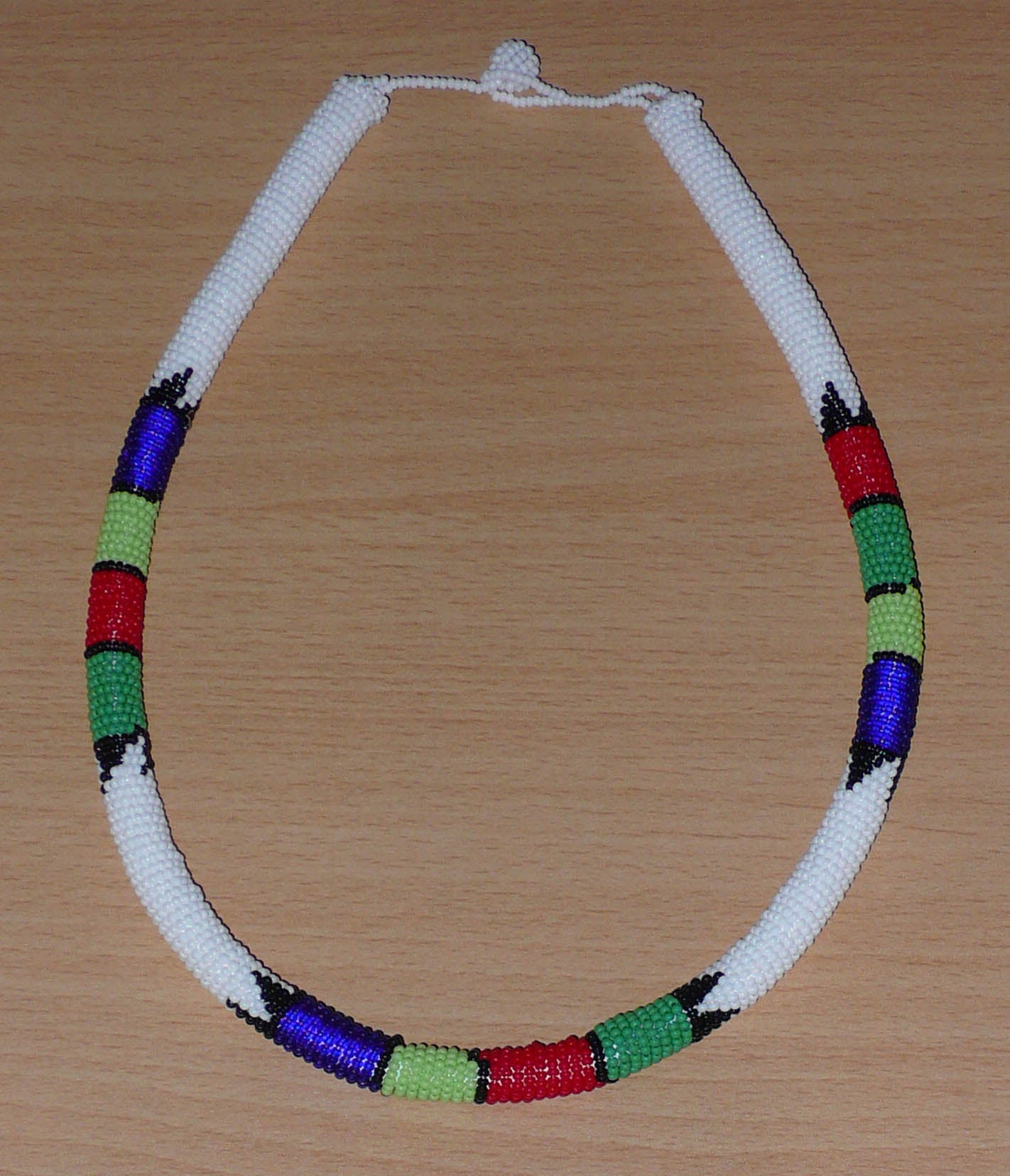 Collier africain tubulaire blanc et multicolore fabriqué en Afrique du Sud composé de perles de rocaille enroulées autour d'un tube en plastique.