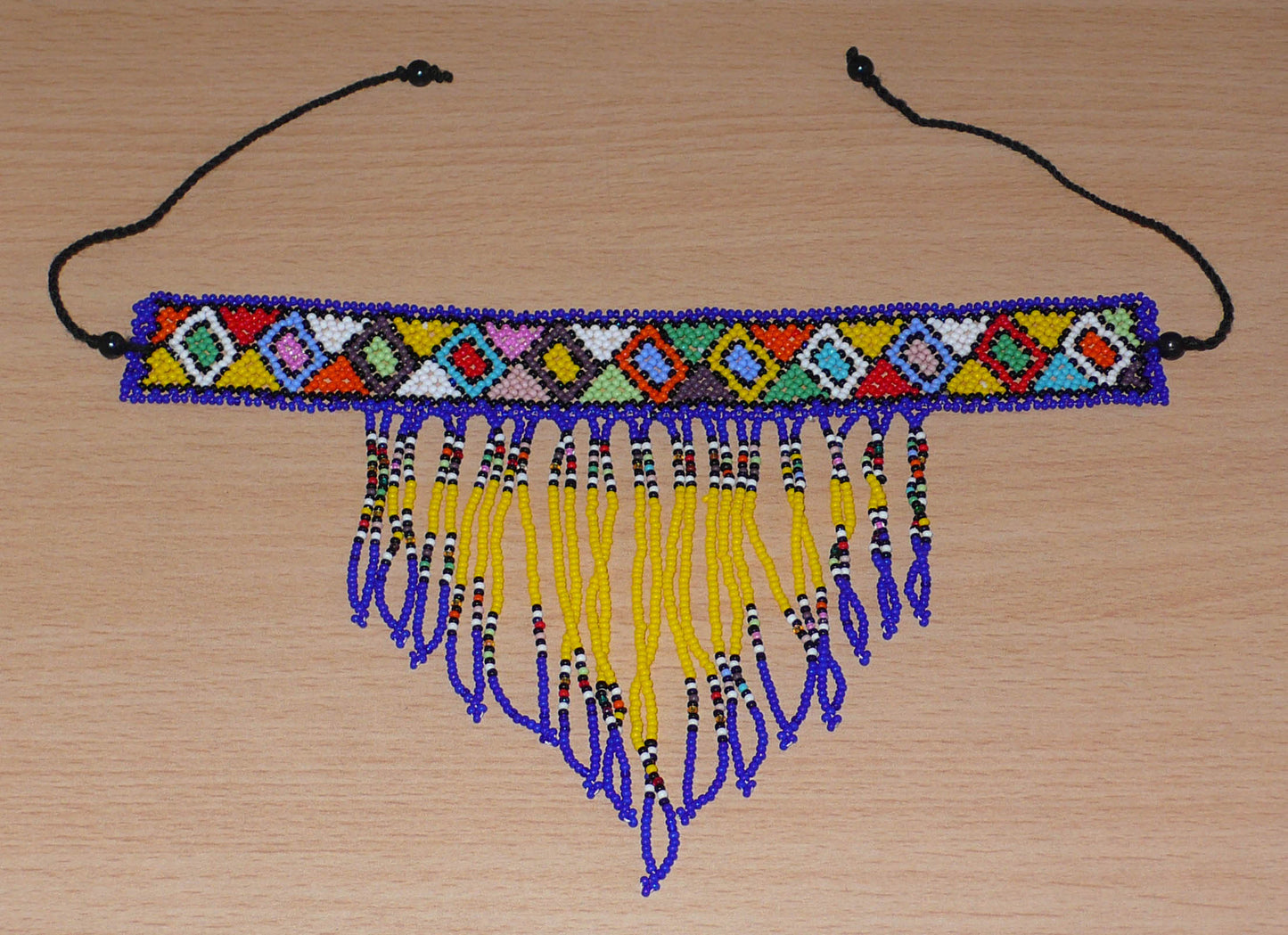 Collier ras de cou sud-africain à franges perlées et motifs ethniques zoulous ; il se compose d'un tissage de perles de rocaille bleues, jaunes et multicolores.